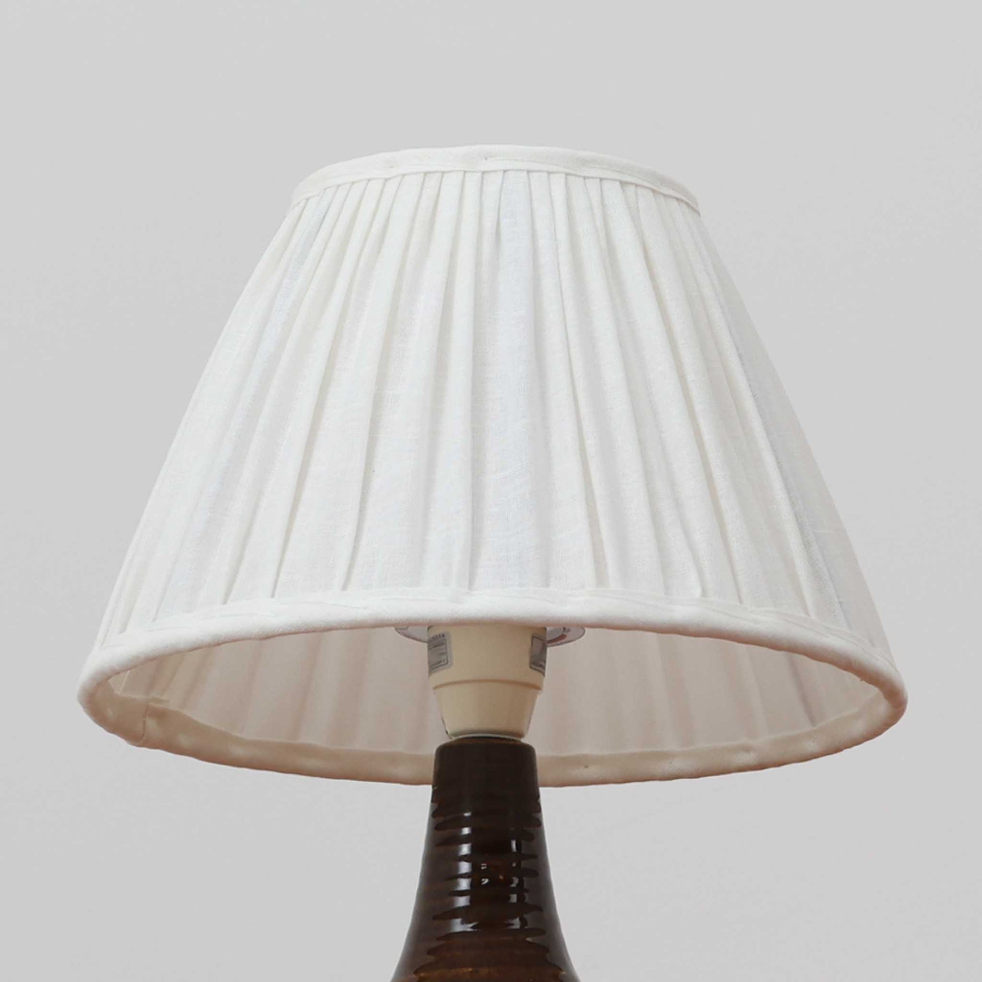 Soholm Keramik（スーホルム・セラミック）が手掛けたモデル1214のテーブルランプは、艶やかなブラウンの釉薬と段状のレリーフが生む豊かな表情が魅力で、陶磁器ならではの重量感と温かみが空間に落ち着いた存在感をもたらす北欧ビンテージ品です。柔らかな光を透過するリネンシェードがやさしい灯りを広げ、ベッドサイドやリビングのアクセント照明として取り入れやすく、経年の風合いが一層味わいを深めています。