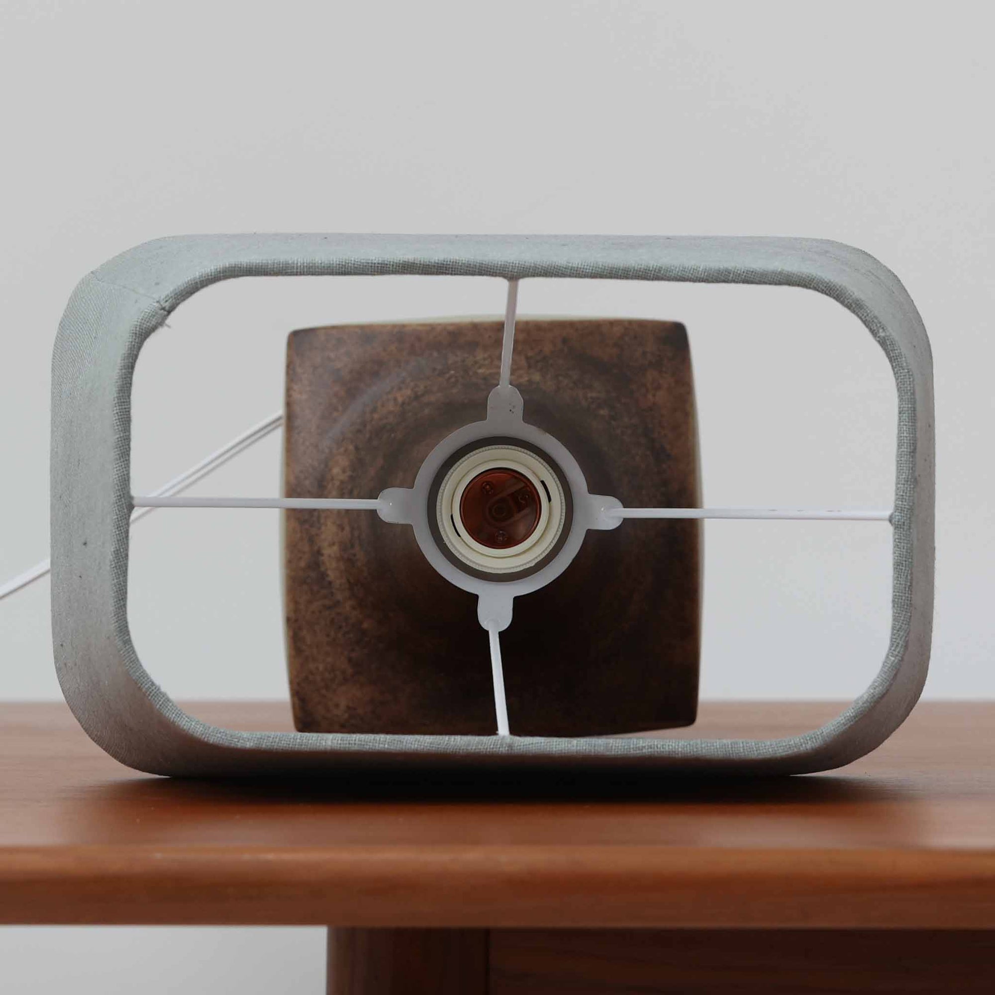 Michael Andersen &amp; Sonが手掛けたこちらのテーブルランプは、陶磁器ならではの落ち着いた質感と、彫刻的に立ち上がるフォルムが存在感を放つ北欧ビンテージ品で、マットブラウンから生成り色へと移ろう釉薬のグラデーションが温かみある陰影を生み出し、リネンシェードを通したやわらかな灯りがベッドサイドやリビングに静かな安らぎを添えます。経年で深まった陶肌の表情がひとつとして同じものがない魅力となり、空間のアクセント照明として長くお楽しみいただける一台です。