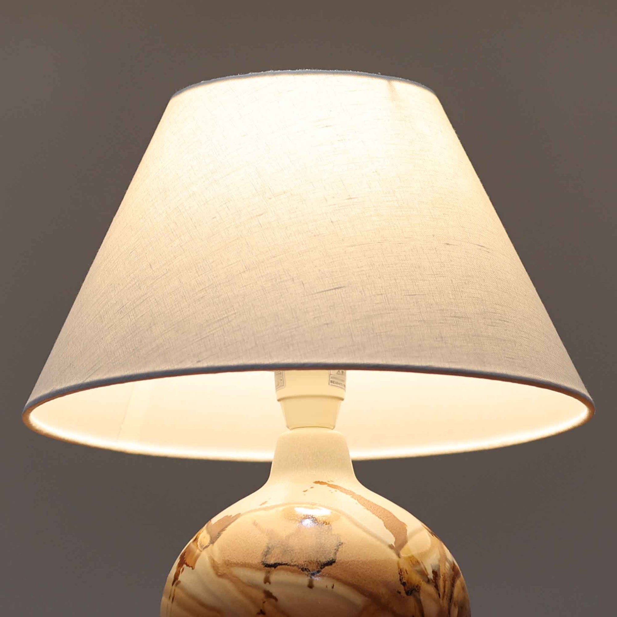 Soholm Keramik（スーホルム・セラミック）が手掛けたこちらのテーブルランプは、淡いグレーを基調にブラウンの流れるような釉薬模様が美しく広がる有機的な表情が魅力で、丸みを帯びた陶磁器のベースが空間にやさしい存在感をもたらす北欧ビンテージ品です。リネンシェードを透ける柔らかな灯りが落ち着いた雰囲気をつくり、ベッドサイドやリビングの間接照明として取り入れやすく、経年によって深まった色合いと一点物ならではの味わいを長く楽しめる一台です。