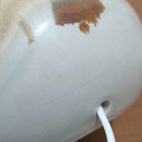 Soholm Keramik（スーホルム・セラミック）が手掛けたこちらのテーブルランプは、淡いグレーを基調にブラウンの流れるような釉薬模様が美しく広がる有機的な表情が魅力で、丸みを帯びた陶磁器のベースが空間にやさしい存在感をもたらす北欧ビンテージ品です。リネンシェードを透ける柔らかな灯りが落ち着いた雰囲気をつくり、ベッドサイドやリビングの間接照明として取り入れやすく、経年によって深まった色合いと一点物ならではの味わいを長く楽しめる一台です。