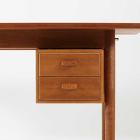 Poul M. Voltherがデザインし、FDB Moblerによって製作された片袖デスク。チーク材の天板と収納部、オーク材の脚部を組み合わせた構成に、真鍮の金具がさりげないアクセントを添える北欧ビンテージらしい一台です。幅160cmのゆとりあるサイズ感に対して、脚部や幕板は軽やかに設計されており、空間に圧迫感を与えません。片側に備えた引き出しユニットは、取り付けた状態でもスライドさせて位置調整が可能で、左右どちら側にも付け替えられる柔軟な構造となっています。さらに引き出しを取り外すことで、デスクとしてだけでなくダイニングテーブルとしても使用でき、暮らしの変化に合わせた使い方ができる点も魅力です。素材ごとの質感の違いと、経年により深みを増した木肌の表情が調和した、長く使い続けたくなるデザインです。