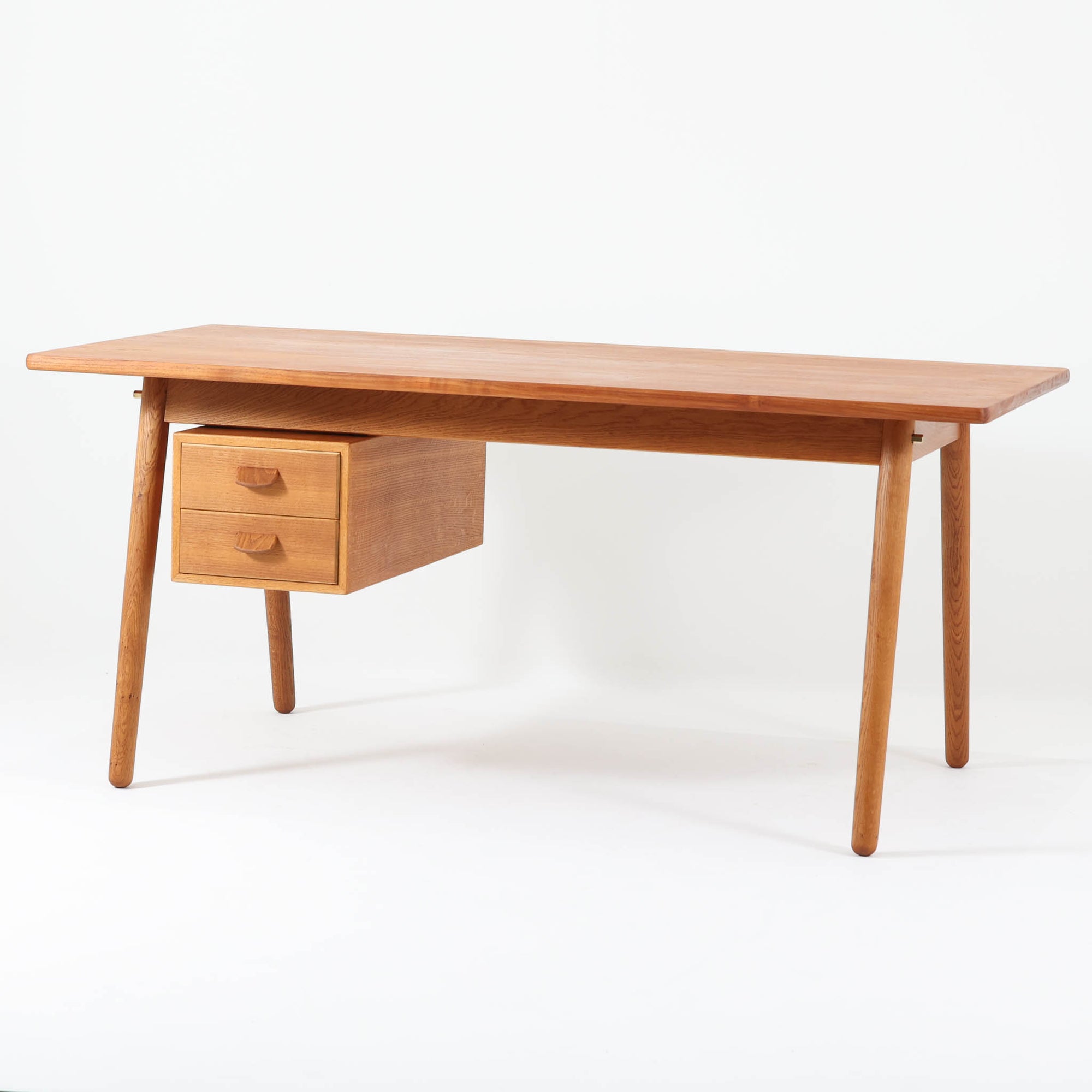 Poul M. Voltherがデザインし、FDB Moblerによって製作された片袖デスク。チーク材の天板と収納部、オーク材の脚部を組み合わせた構成に、真鍮の金具がさりげないアクセントを添える北欧ビンテージらしい一台です。幅160cmのゆとりあるサイズ感に対して、脚部や幕板は軽やかに設計されており、空間に圧迫感を与えません。片側に備えた引き出しユニットは、取り付けた状態でもスライドさせて位置調整が可能で、左右どちら側にも付け替えられる柔軟な構造となっています。さらに引き出しを取り外すことで、デスクとしてだけでなくダイニングテーブルとしても使用でき、暮らしの変化に合わせた使い方ができる点も魅力です。素材ごとの質感の違いと、経年により深みを増した木肌の表情が調和した、長く使い続けたくなるデザインです。