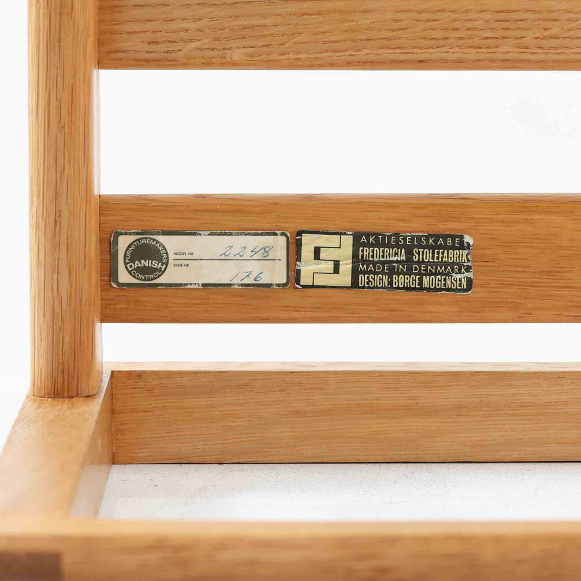 Borge Mogensenがデザインし、Fredericia社より製作されたModel 2248のオットマンです。オーク材を使用した堅牢なフレームは、北欧家具らしいシンプルで実用性を重視したデザインが魅力。直線的で無駄のない構造と、丁寧な木工による美しい仕上げが、モーエンセンの哲学を感じさせます。クッションにはやわらかなファブリックを張り、快適な座り心地を実現。オットマンとして足を休める用途はもちろん、スツールや補助椅子としても活躍します。同シリーズのラウンジチェアと組み合わせることで、より快適なくつろぎの空間を演出できる、北欧ビンテージならではの機能美を備えた一品です。