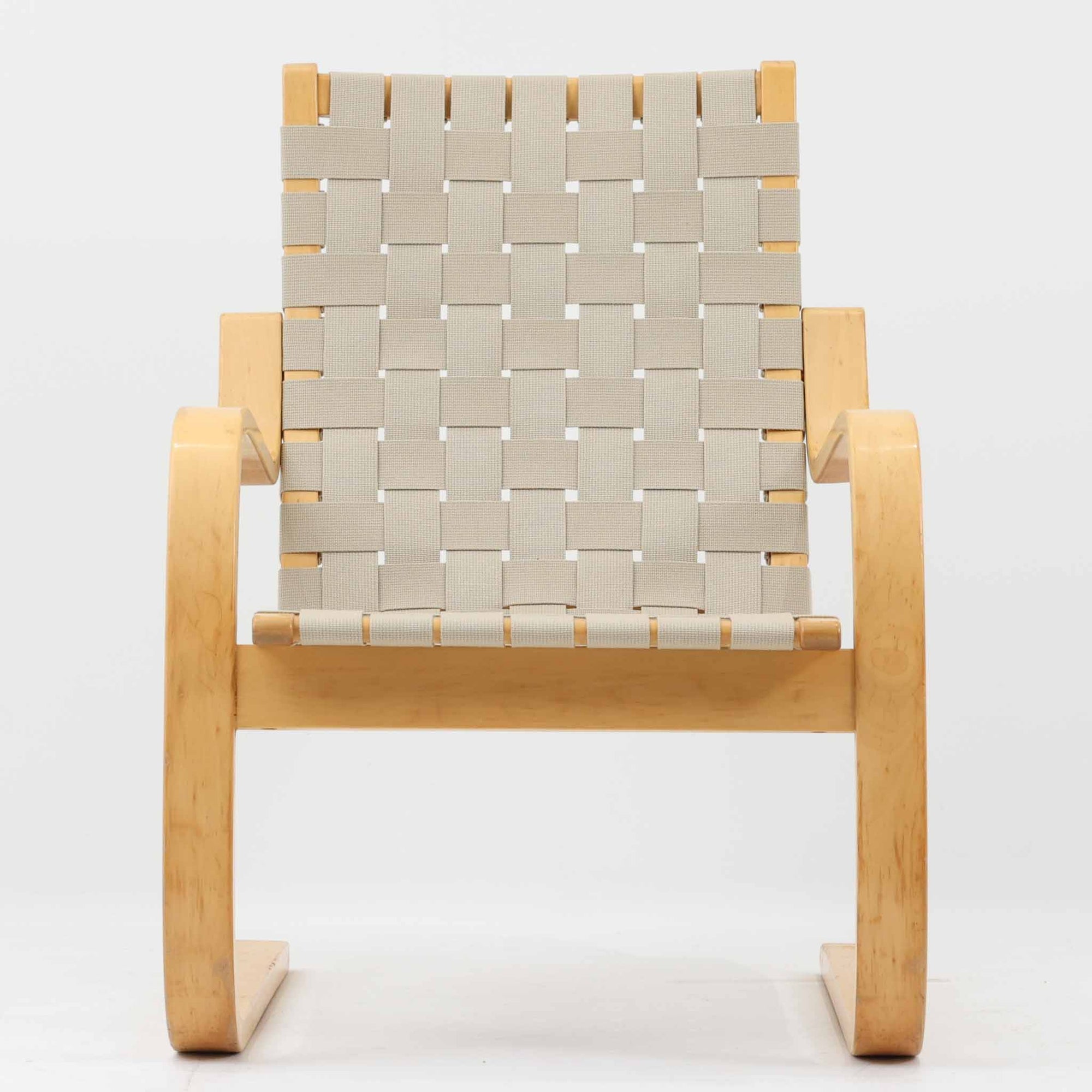 Alvar Aaltoがデザインし、Artekより製作されたNo.406アームチェアです。しなやかな曲線を描くバーチ材の成形フレームが特徴で、浮遊感のあるフォルムと軽やかな佇まいが空間に北欧らしい美しさをもたらします。座面と背もたれにはウェビングテープが張られ、適度な弾力と通気性の良い快適な座り心地を実現。アアルトの有機的なデザイン思想が感じられる一脚で、リビングやラウンジでの寛ぎの時間を彩るビンテージチェアです。