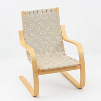 Alvar Aaltoがデザインし、Artekより製作されたNo.406アームチェアです。しなやかな曲線を描くバーチ材の成形フレームが特徴で、浮遊感のあるフォルムと軽やかな佇まいが空間に北欧らしい美しさをもたらします。本品は1996年製の個体で、ビンテージならではの雰囲気をお楽しみいただけます。座面と背もたれにはウェビングテープが張られ、適度な弾力と通気性の良い快適な座り心地を実現。アアルトの有機的なデザイン思想が感じられる一脚で、リビングやラウンジでの寛ぎの時間を彩るビンテージチェアです。