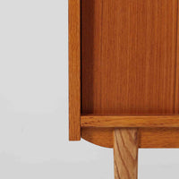 スウェーデン製のこちらのオープンシェルフは、チーク材の温かな木目とオーク材の脚部を組み合わせた軽やかな佇まいが魅力で、上段の棚板と下段のスライド扉収納を備えた実用性の高い構成が特徴の北欧ビンテージ家具です。丸い掘り込み取手や細身のフレームなど繊細なディテールが空間を柔らかく彩り、本や雑貨、食器などを美しく見せながら整頓でき、経年で深まった木肌の風合いがインテリアに落ち着きと温もりを与える一台です。