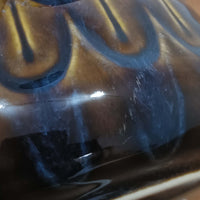 Einar JohansenがSoholm Keramik（スーホルム・セラミック）のために手掛けたモデル1015は、深いブラウンの釉薬に美しい光沢が宿り、ベースを覆う羽根模様のようなレリーフが立体的な表情を生み出す北欧ビンテージの名品で、すっきりと立ち上がるシルエットと陶磁器ならではの重厚感が空間に落ち着いた存在感をもたらします。リネンシェードを通したやわらかな灯りはベッドサイドやリビングに 温かみを添え、経年の風合いが一点物としての魅力をより一層引き立てています。