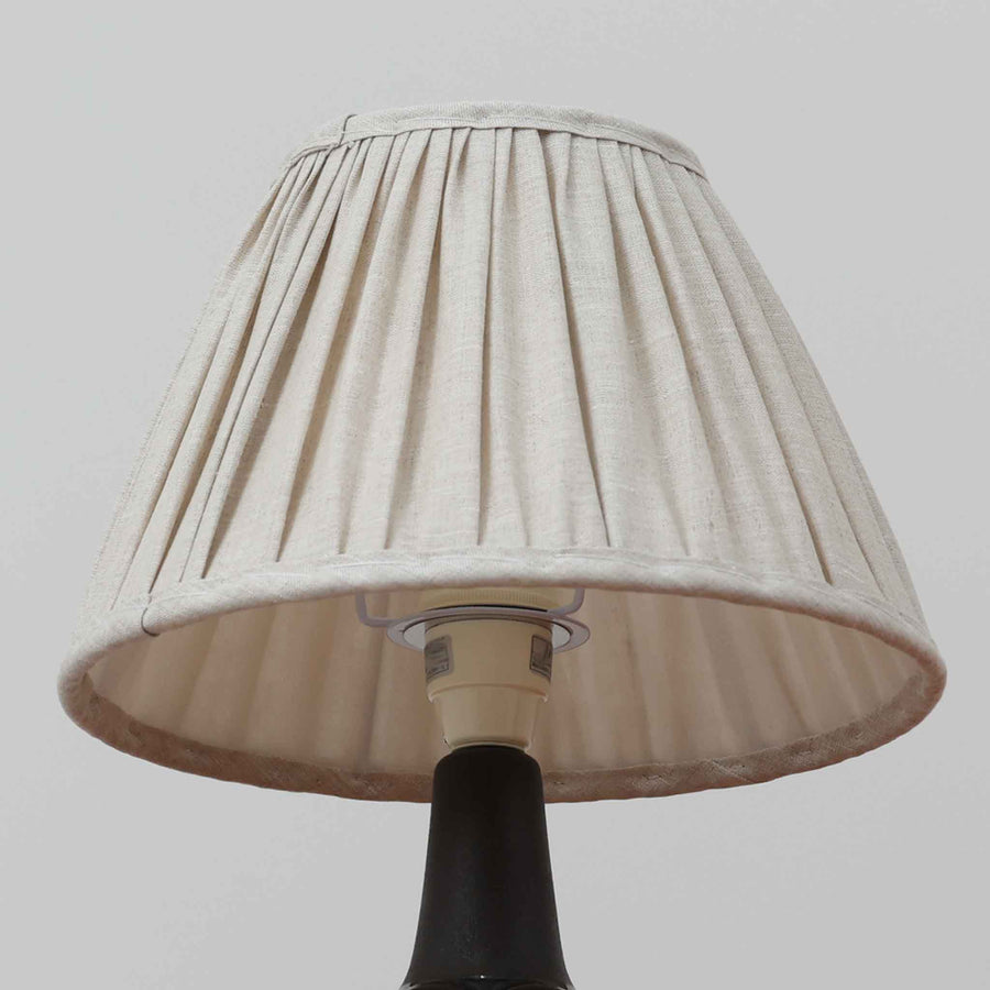 Einar JohansenがSoholm Keramik（スーホルム・セラミック）のためにデザインしたモデル1031は、深みのあるブルーの釉薬と立体的な面取りが織りなす陰影が美しい陶磁器ベースが特徴で、上部のマットな質感との対比がモダンで彫刻的な存在感を放つ北欧ビンテージ品です。プリーツシェードを透ける柔らかな灯りが落ち着いた雰囲気をつくり、ベッドサイドやリビングのアクセント照明として取り入れやすく、経年で深まった釉薬の表情が一点物ならではの魅力を一層引き立てています。