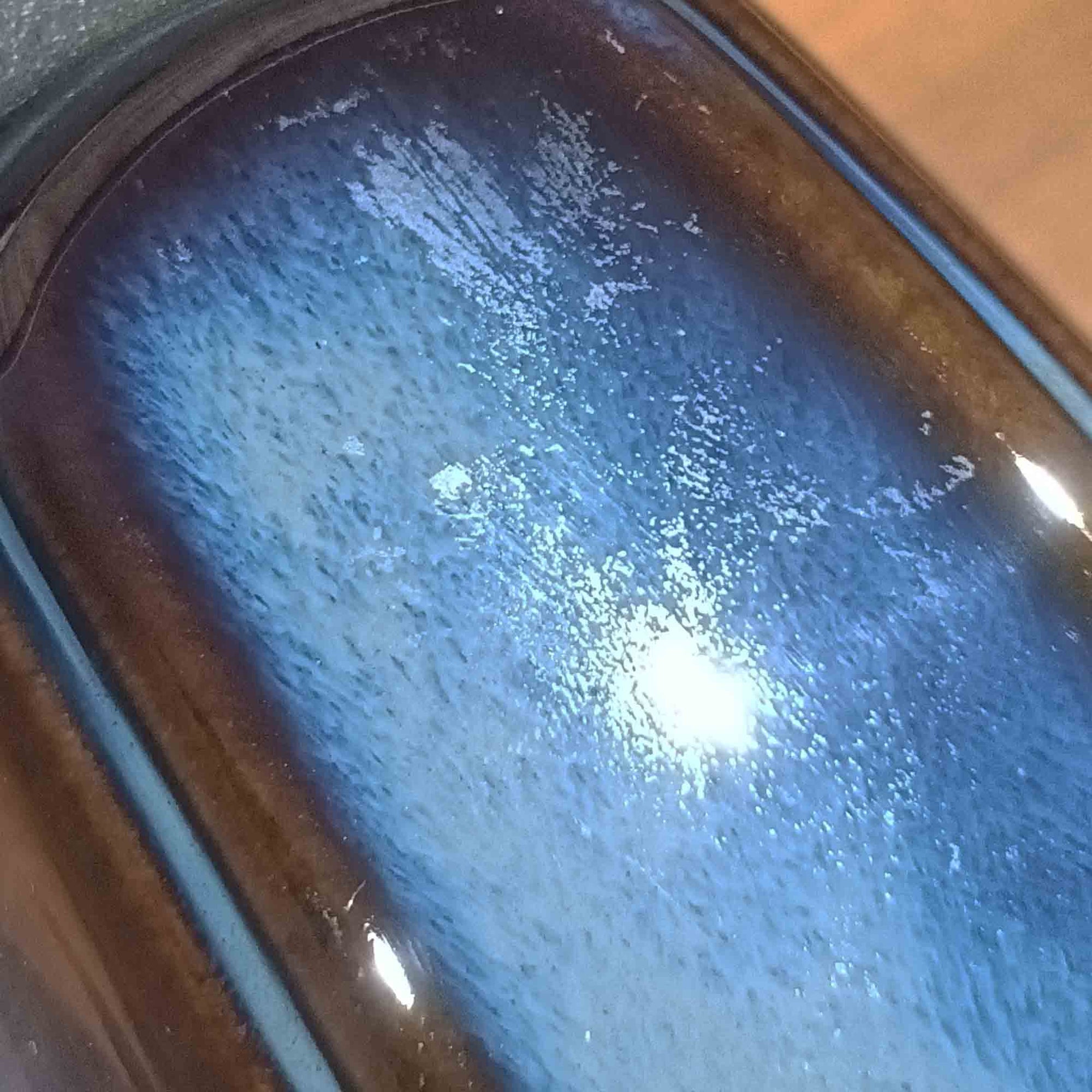 Einar JohansenがSoholm Keramik（スーホルム・セラミック）のためにデザインしたモデル1031は、深みのあるブルーの釉薬と立体的な面取りが織りなす陰影が美しい陶磁器ベースが特徴で、上部のマットな質感との対比がモダンで彫刻的な存在感を放つ北欧ビンテージ品です。プリーツシェードを透ける柔らかな灯りが落ち着いた雰囲気をつくり、ベッドサイドやリビングのアクセント照明として取り入れやすく、経年で深まった釉薬の表情が一点物ならではの魅力を一層引き立てています。