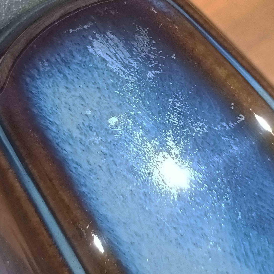 Einar JohansenがSoholm Keramik（スーホルム・セラミック）のためにデザインしたモデル1031は、深みのあるブルーの釉薬と立体的な面取りが織りなす陰影が美しい陶磁器ベースが特徴で、上部のマットな質感との対比がモダンで彫刻的な存在感を放つ北欧ビンテージ品です。プリーツシェードを透ける柔らかな灯りが落ち着いた雰囲気をつくり、ベッドサイドやリビングのアクセント照明として取り入れやすく、経年で深まった釉薬の表情が一点物ならではの魅力を一層引き立てています。