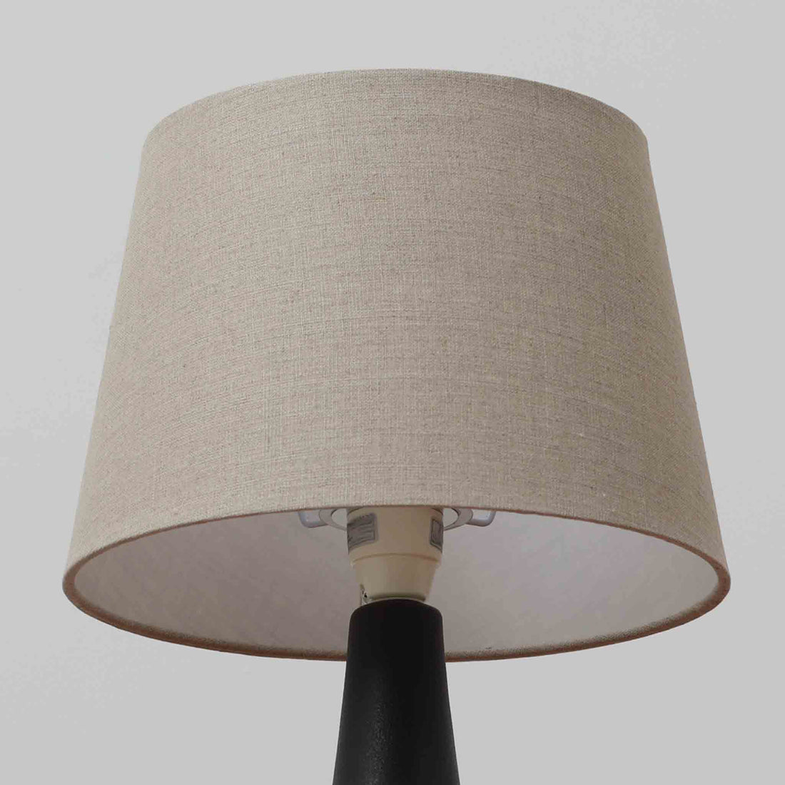 Einar JohansenがSoholm Keramik（スーホルム・セラミック）のために手掛けたモデル1038は、深みのあるブルーの釉薬が重なり合うように陰影をつくる陶磁器ベースと、上部のマットな質感とのコントラストが美しい北欧ビンテージ品で、四面に施された力強いレリーフ装飾が彫刻的な存在感を与えます。リネンシェード越しに広がる柔らかな灯りが空間を優しく包み込み、リビングやベッドサイドのアクセント照明として取り入れやすく、経年で深まった釉薬の表情が一点物ならではの味わいを一層引き立てています。