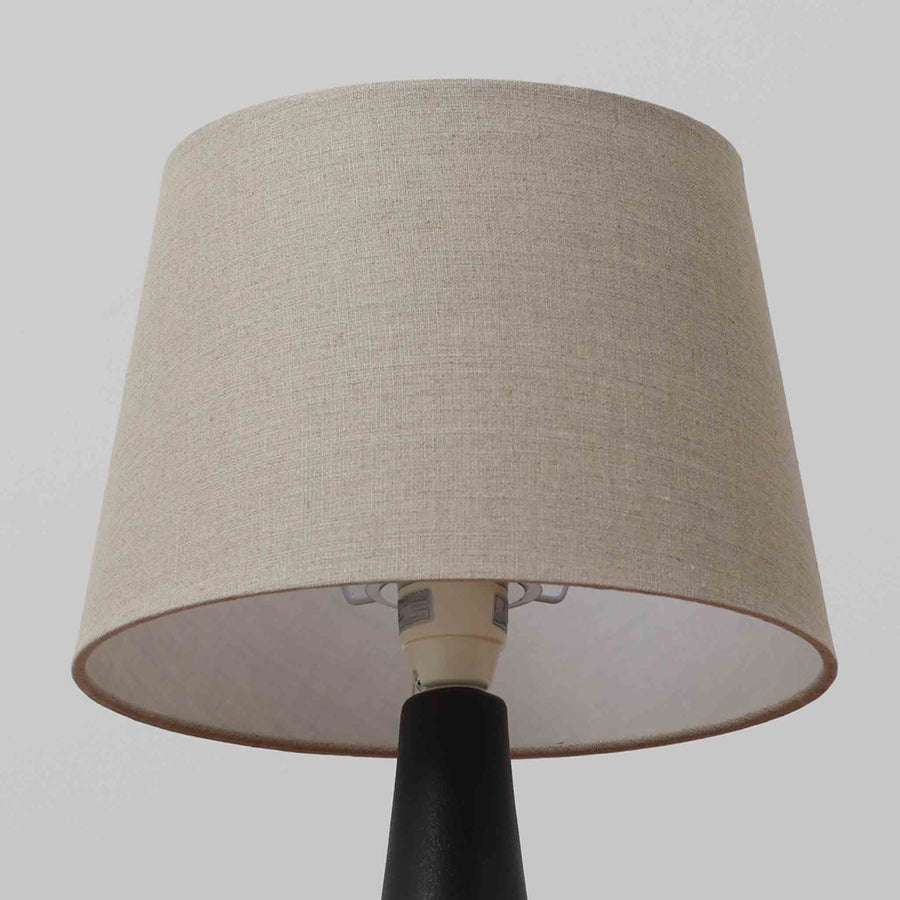 Einar JohansenがSoholm Keramik（スーホルム・セラミック）のために手掛けたモデル1038は、深みのあるブルーの釉薬が重なり合うように陰影をつくる陶磁器ベースと、上部のマットな質感とのコントラストが美しい北欧ビンテージ品で、四面に施された力強いレリーフ装飾が彫刻的な存在感を与えます。リネンシェード越しに広がる柔らかな灯りが空間を優しく包み込み、リビングやベッドサイドのアクセント照明として取り入れやすく、経年で深まった釉薬の表情が一点物ならではの味わいを一層引き立てています。