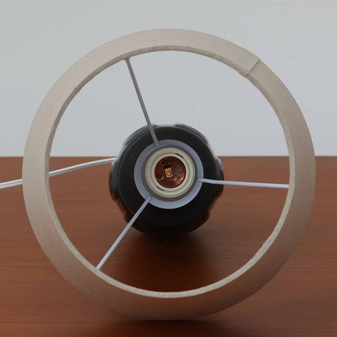 Einar JohansenがSoholm Keramik（スーホルム・セラミック）のために手掛けたモデル1038は、深みのあるブルーの釉薬が重なり合うように陰影をつくる陶磁器ベースと、上部のマットな質感とのコントラストが美しい北欧ビンテージ品で、四面に施された力強いレリーフ装飾が彫刻的な存在感を与えます。リネンシェード越しに広がる柔らかな灯りが空間を優しく包み込み、リビングやベッドサイドのアクセント照明として取り入れやすく、経年で深まった釉薬の表情が一点物ならではの味わいを一層引き立てています。