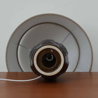 Einar JohansenがSoholm Keramik（スーホルム・セラミック）のために手掛けたモデル1038は、深みのあるブルーの釉薬が重なり合うように陰影をつくる陶磁器ベースと、上部のマットな質感とのコントラストが美しい北欧ビンテージ品で、四面に施された力強いレリーフ装飾が彫刻的な存在感を与えます。リネンシェード越しに広がる柔らかな灯りが空間を優しく包み込み、リビングやベッドサイドのアクセント照明として取り入れやすく、経年で深まった釉薬の表情が一点物ならではの味わいを一層引き立てています。