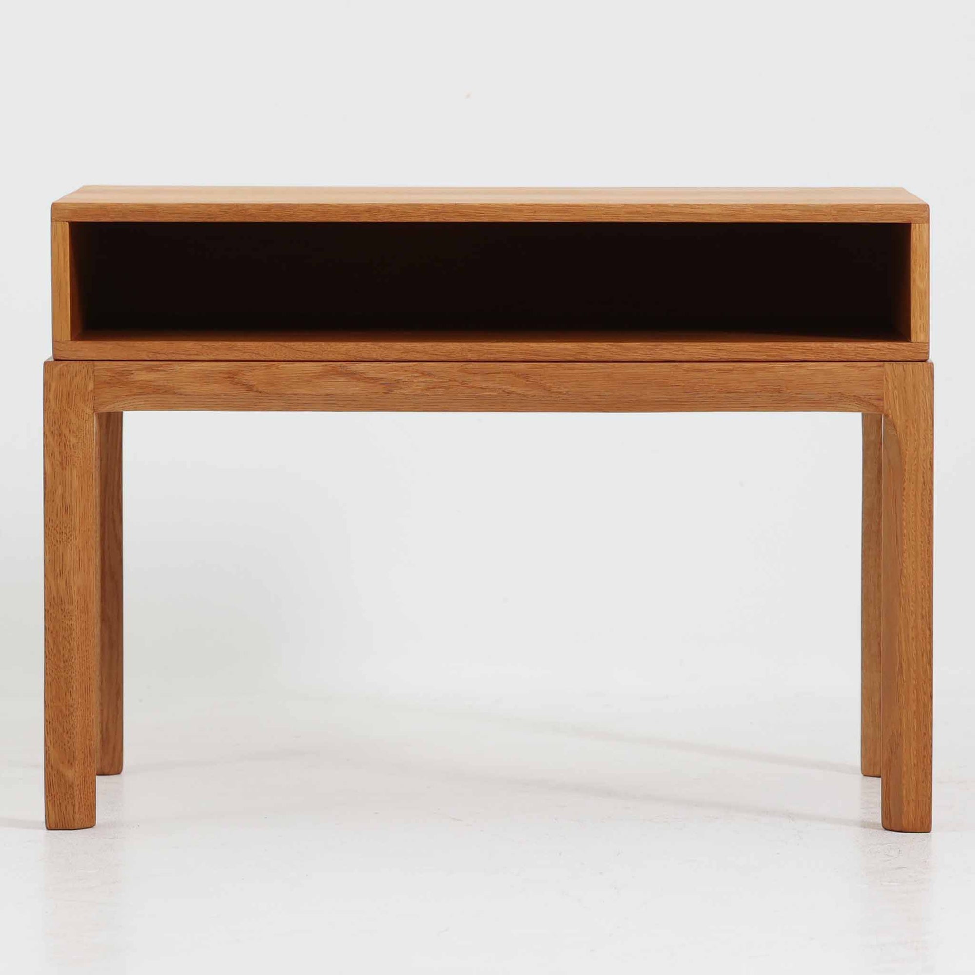 デンマークのデザイナー、カイ・クリスチャンセンによるデザイン、Aksel Kjersgaard社製のサイドテーブル「No.383」です。オーク材を用いた端正な造りで、脚部の滑らかなカーブや接合部の美しいラインなど、北欧家具の職人技が随所に感じられます。天板下には小物を収納できるスペースが設けられ、実用性とデザイン性を兼ね備えた構造です。経年によるオークの柔らかな風合いが魅力で、ベッドサイドやリビングのアクセントとしてもおすすめの一台です。