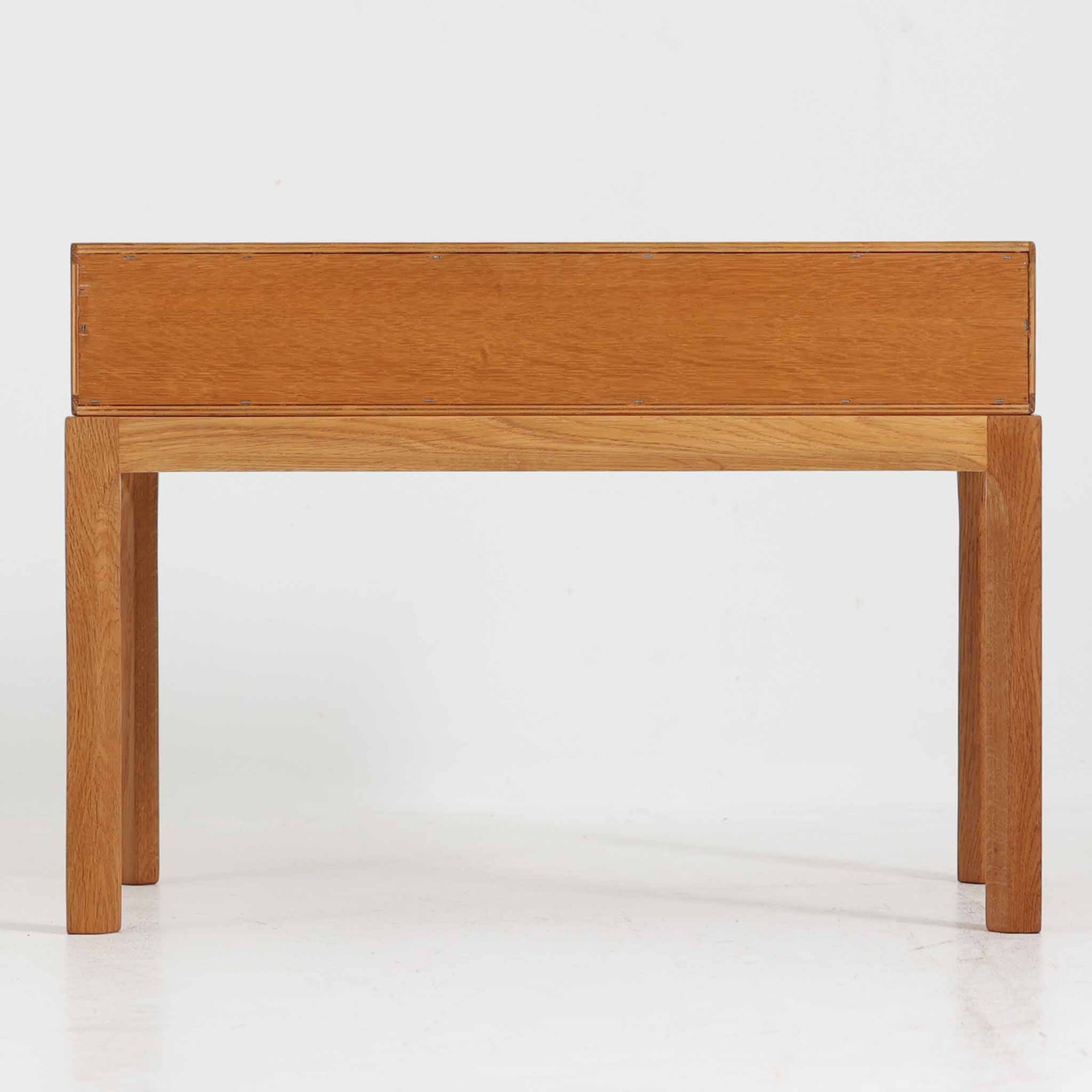 デンマークのデザイナー、カイ・クリスチャンセンによるデザイン、Aksel Kjersgaard社製のサイドテーブル「No.383」です。オーク材を用いた端正な造りで、脚部の滑らかなカーブや接合部の美しいラインなど、北欧家具の職人技が随所に感じられます。天板下には小物を収納できるスペースが設けられ、実用性とデザイン性を兼ね備えた構造です。経年によるオークの柔らかな風合いが魅力で、ベッドサイドやリビングのアクセントとしてもおすすめの一台です。