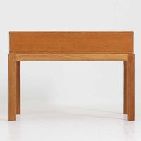 デンマークのデザイナー、カイ・クリスチャンセンによるデザイン、Aksel Kjersgaard社製のサイドテーブル「No.383」です。オーク材を用いた端正な造りで、脚部の滑らかなカーブや接合部の美しいラインなど、北欧家具の職人技が随所に感じられます。天板下には小物を収納できるスペースが設けられ、実用性とデザイン性を兼ね備えた構造です。経年によるオークの柔らかな風合いが魅力で、ベッドサイドやリビングのアクセントとしてもおすすめの一台です。