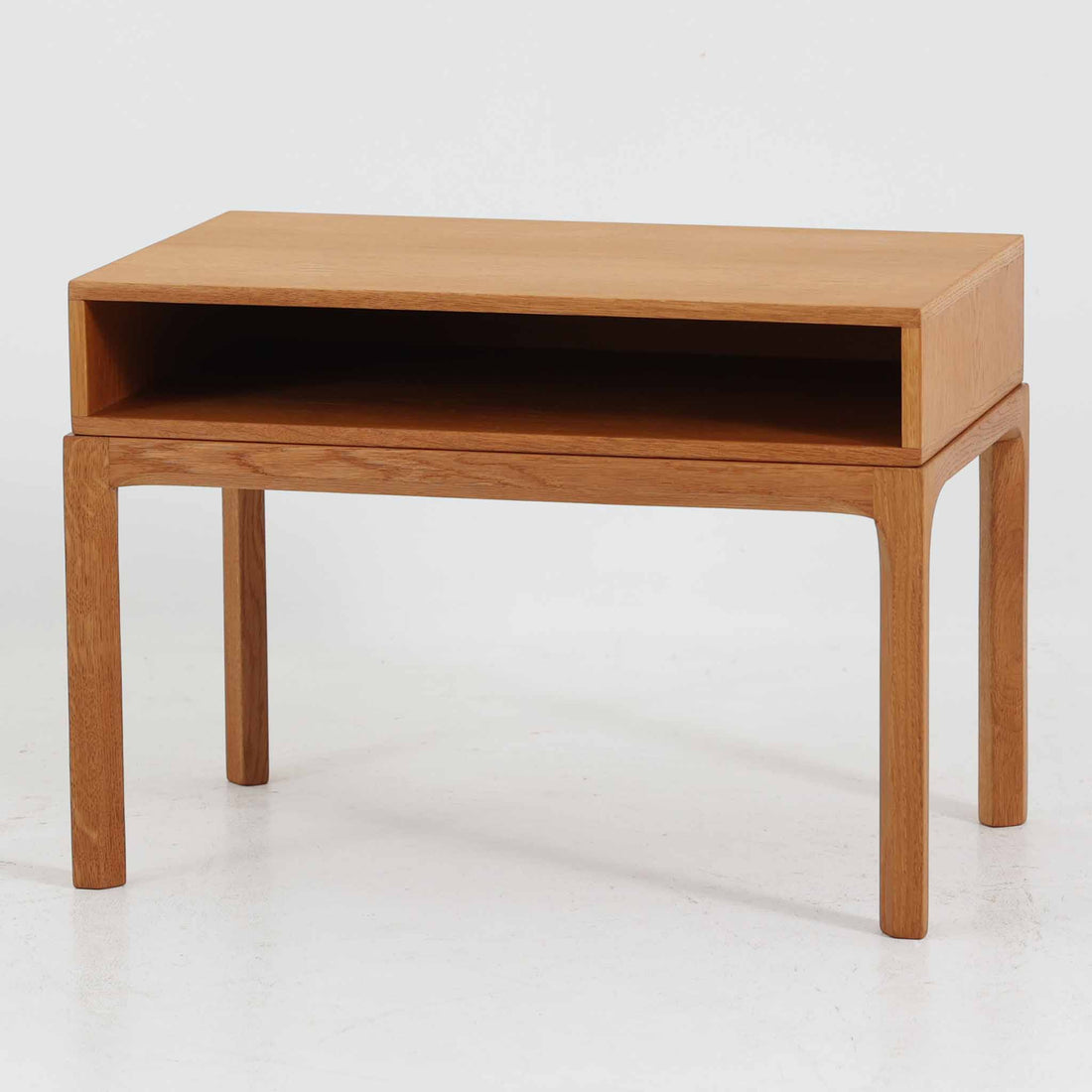 デンマークのデザイナー、カイ・クリスチャンセンによるデザイン、Aksel Kjersgaard社製のサイドテーブル「No.383」です。オーク材を用いた端正な造りで、脚部の滑らかなカーブや接合部の美しいラインなど、北欧家具の職人技が随所に感じられます。天板下には小物を収納できるスペースが設けられ、実用性とデザイン性を兼ね備えた構造です。経年によるオークの柔らかな風合いが魅力で、ベッドサイドやリビングのアクセントとしてもおすすめの一台です。