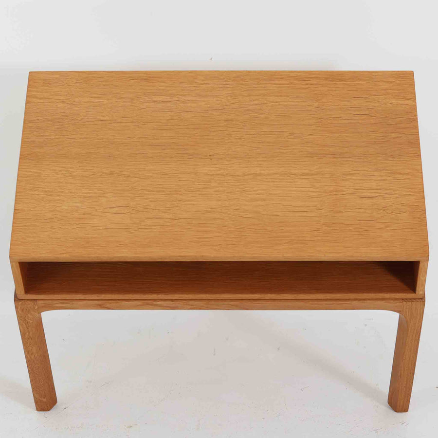 デンマークのデザイナー、カイ・クリスチャンセンによるデザイン、Aksel Kjersgaard社製のサイドテーブル「No.383」です。オーク材を用いた端正な造りで、脚部の滑らかなカーブや接合部の美しいラインなど、北欧家具の職人技が随所に感じられます。天板下には小物を収納できるスペースが設けられ、実用性とデザイン性を兼ね備えた構造です。経年によるオークの柔らかな風合いが魅力で、ベッドサイドやリビングのアクセントとしてもおすすめの一台です。