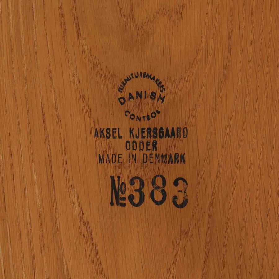 デンマークのデザイナー、カイ・クリスチャンセンによるデザイン、Aksel Kjersgaard社製のサイドテーブル「No.383」です。オーク材を用いた端正な造りで、脚部の滑らかなカーブや接合部の美しいラインなど、北欧家具の職人技が随所に感じられます。天板下には小物を収納できるスペースが設けられ、実用性とデザイン性を兼ね備えた構造です。経年によるオークの柔らかな風合いが魅力で、ベッドサイドやリビングのアクセントとしてもおすすめの一台です。