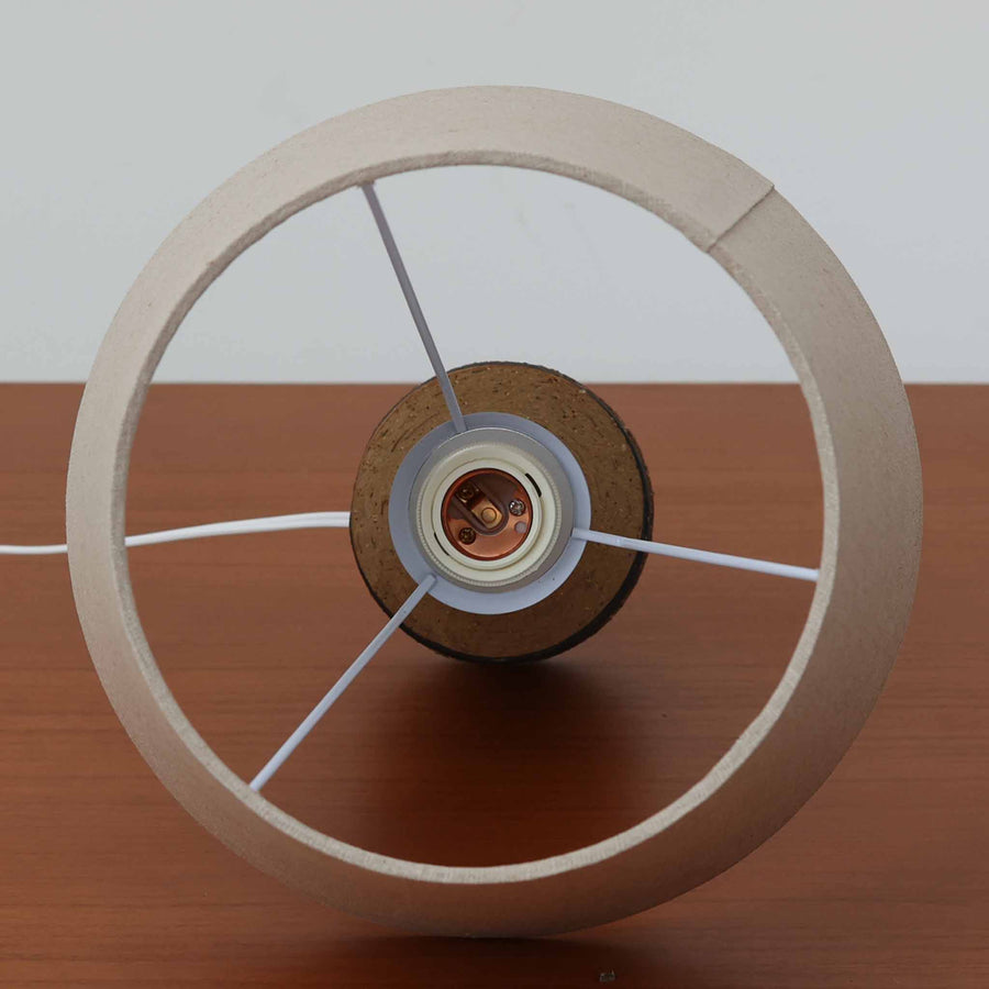 Jette HelleroeがAxellaのために手掛けたこちらのテーブルランプは、砂質の陶肌を生かした素朴で温かみのある質感と、ベース部分にぐるりと施された幾何学的なレリーフ装飾が印象的で、手仕事の風合いが際立つ北欧ビンテージ品です。すらりと立ち上がるシルエットが軽やかなバランスをつくり、リネンシェードを透ける柔らかな灯りがリビングやベッドサイドに落ち着いた雰囲気を添え、経年で深まった土味と装飾の陰影が一点物ならではの魅力を一層引き立てています。