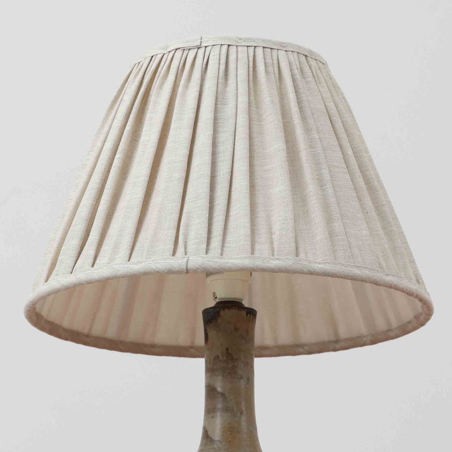 Axella製のこちらのテーブルランプは、素地を生かした陶土の質感に流れるような釉薬のグラデーションが重なり合う有機的な表情が魅力で、ぽってりとした丸みのあるフォルムと細く立ち上がる首部の対比が北欧らしい温かみのある佇まいを生み出すビンテージ品です。手仕事ならではの不均一な釉薬の景色が一点物の存在感を与え、リネンシェードからこぼれる柔らかな灯りがリビングや寝室に落ち着いた雰囲気を添え、経年で深まった陶肌の風合いが空間に自然なアクセントを加えてくれます。