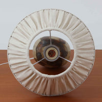 Axella製のこちらのテーブルランプは、素地を生かした陶土の質感に流れるような釉薬のグラデーションが重なり合う有機的な表情が魅力で、ぽってりとした丸みのあるフォルムと細く立ち上がる首部の対比が北欧らしい温かみのある佇まいを生み出すビンテージ品です。手仕事ならではの不均一な釉薬の景色が一点物の存在感を与え、リネンシェードからこぼれる柔らかな灯りがリビングや寝室に落ち着いた雰囲気を添え、経年で深まった陶肌の風合いが空間に自然なアクセントを加えてくれます。