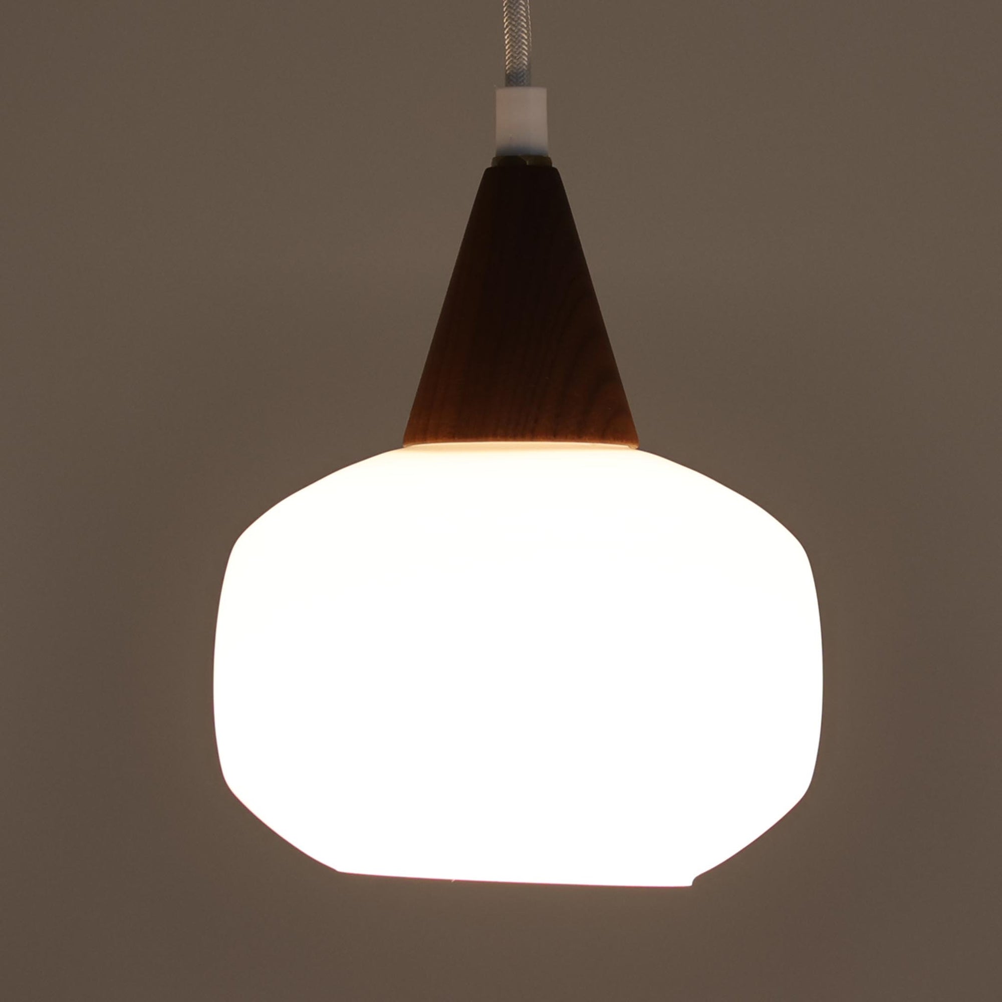 丸みを帯びた乳白ガラスシェードに温かみのあるウッドパーツを組み合わせた直径14cmのペンダントライトで、柔らかい光がふんわりと広がり、小空間に落ち着いた表情をもたらす北欧ビンテージ品です。シンプルながらもコロンとした可愛らしいフォルムがアクセントとなり、玄関や廊下、キッチンカウンターなど限られたスペースにも取り入れやすいサイズ感が魅力です。ガラス越しの柔らかな光とウッドの自然な表情が調和し、経年で深まった素材の風合いがビンテージならではの温もりを感じさせてくれます。