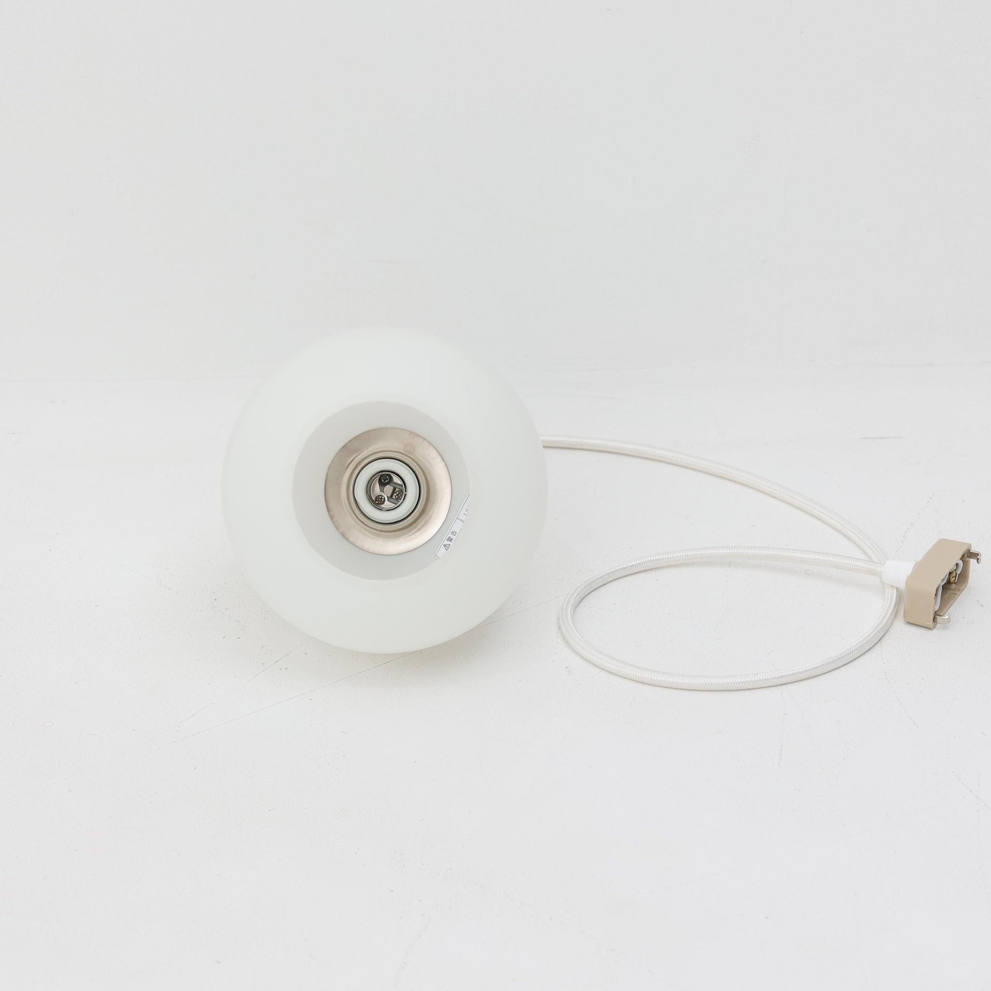 丸みを帯びた乳白ガラスシェードに温かみのあるウッドパーツを組み合わせた直径14cmのペンダントライトで、柔らかい光がふんわりと広がり、小空間に落ち着いた表情をもたらす北欧ビンテージ品です。シンプルながらもコロンとした可愛らしいフォルムがアクセントとなり、玄関や廊下、キッチンカウンターなど限られたスペースにも取り入れやすいサイズ感が魅力です。ガラス越しの柔らかな光とウッドの自然な表情が調和し、経年で深まった素材の風合いがビンテージならではの温もりを感じさせてくれます。