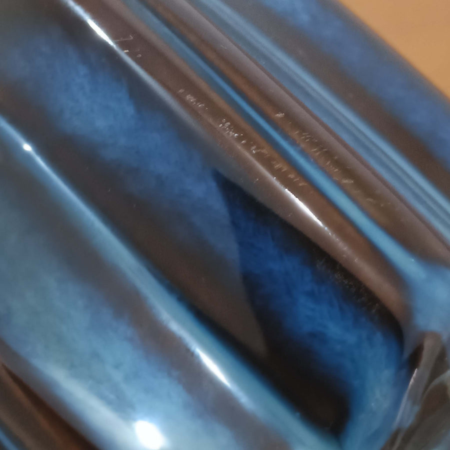 Einar JohansenがSoholm Keramikのために手掛けたモデル「1052」は、濃淡のある深いブルーグラデーションと面取りを施した立体的なフォルムが美しく、上部のマットな質感とのコントラストが上品な存在感を生む北欧ビンテージのテーブルランプです。柔らかく広がるリネンシェードの灯りが陰影豊かな陶肌をやさしく照らし、リビングや寝室のアクセントとして取り入れやすく、経年で深まった釉薬の表情が一点物ならではの味わいを引き立てています。