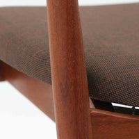 Kai Kristiansenがデザインし、Magnus Olesenが製作したTrojaアームチェアです。アフロモシア材の滑らかな木肌と深みのある色合いが美しく、背からアームへと一体で削り出されたフレームが身体をやさしく包み込みます。わずかに湾曲した笠木や細身の脚部が軽快な印象を与え、立ち座りの動作も自然。張り替え済みの座面は快適な掛け心地を備え、ダイニングや書斎空間に北欧ビンテージならではの気品と造形美をもたらす一脚です。ロゴは、デンマークの家具販売店（小売店）である Brdr. Ellehuus（エルフース兄弟店） のものです。