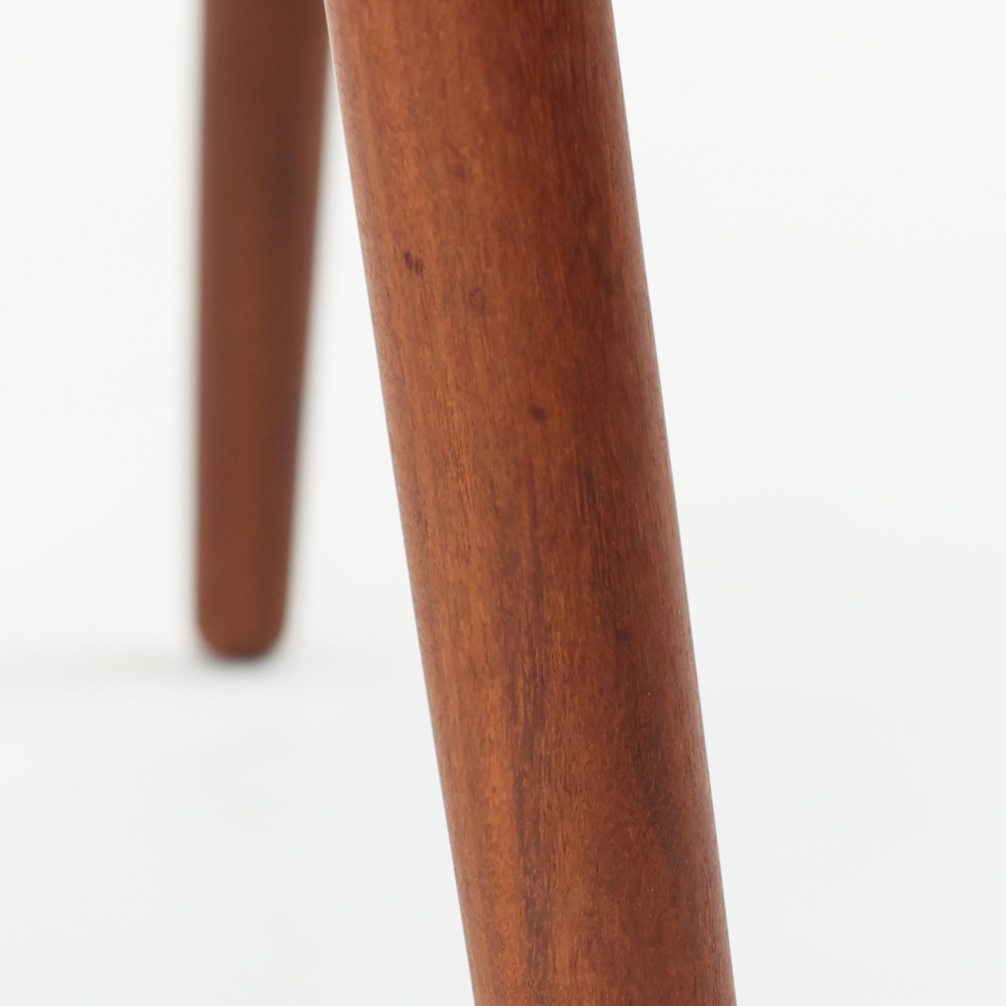 Kai Kristiansenがデザインし、Magnus Olesenが製作したTrojaアームチェアです。アフロモシア材の滑らかな木肌と深みのある色合いが美しく、背からアームへと一体で削り出されたフレームが身体をやさしく包み込みます。わずかに湾曲した笠木や細身の脚部が軽快な印象を与え、立ち座りの動作も自然。張り替え済みの座面は快適な掛け心地を備え、ダイニングや書斎空間に北欧ビンテージならではの気品と造形美をもたらす一脚です。ロゴは、デンマークの家具販売店（小売店）である Brdr. Ellehuus（エルフース兄弟店） のものです。