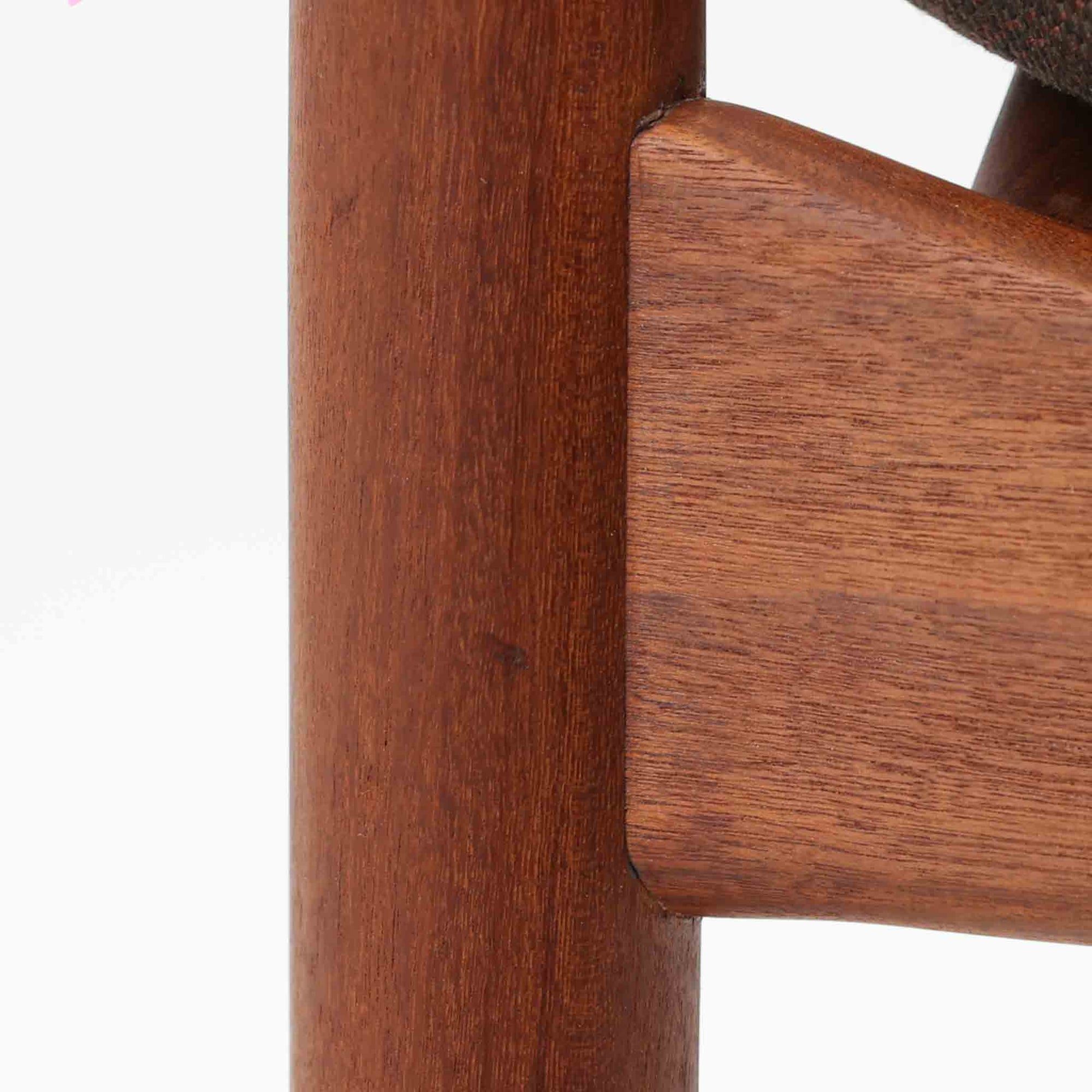 Kai Kristiansenがデザインし、Magnus Olesenが製作したTrojaアームチェアです。アフロモシア材の滑らかな木肌と深みのある色合いが美しく、背からアームへと一体で削り出されたフレームが身体をやさしく包み込みます。わずかに湾曲した笠木や細身の脚部が軽快な印象を与え、立ち座りの動作も自然。張り替え済みの座面は快適な掛け心地を備え、ダイニングや書斎空間に北欧ビンテージならではの気品と造形美をもたらす一脚です。ロゴは、デンマークの家具販売店（小売店）である Brdr. Ellehuus（エルフース兄弟店） のものです。