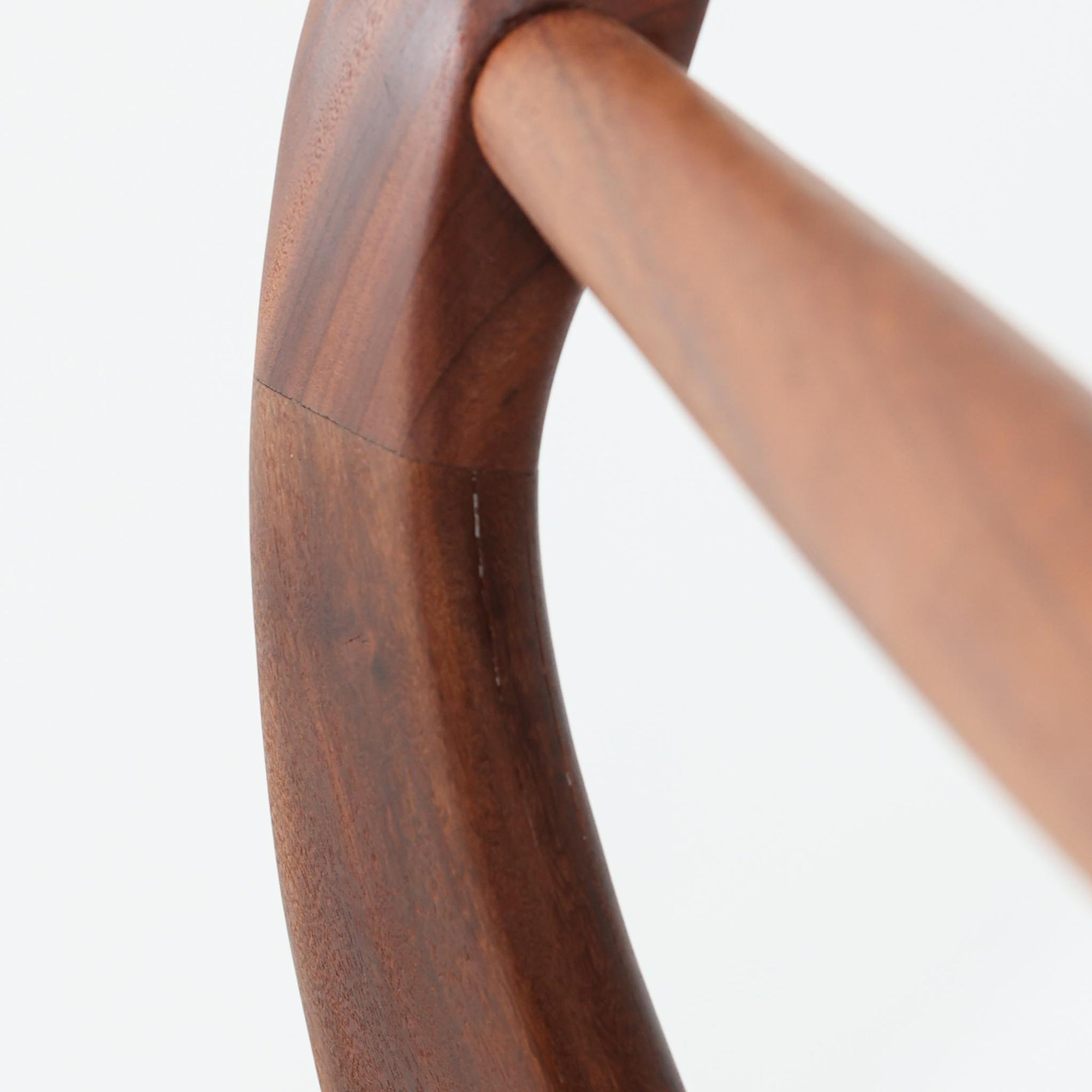 Kai Kristiansenがデザインし、Magnus Olesenが製作したTrojaアームチェアです。アフロモシア材の滑らかな木肌と深みのある色合いが美しく、背からアームへと一体で削り出されたフレームが身体をやさしく包み込みます。わずかに湾曲した笠木や細身の脚部が軽快な印象を与え、立ち座りの動作も自然。張り替え済みの座面は快適な掛け心地を備え、ダイニングや書斎空間に北欧ビンテージならではの気品と造形美をもたらす一脚です。ロゴは、デンマークの家具販売店（小売店）である Brdr. Ellehuus（エルフース兄弟店） のものです。