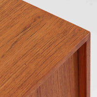 Kai Kristiansenがデザインし、Feldballes Mobelfabrikが製作した幅86cmの小ぶりなボードです。チーク材の美しい木目を活かした端正な箱型フォルムに、丸い引き手付きの引き戸がアクセントを添えます。内部には棚とトレー収納を備え、書類や小物を整理しやすい実用的な構造。すらりと伸びる脚部が軽やかさを演出し、限られた空間にも取り入れやすいサイズ感です。経年により深みを増した木肌が、北欧ビンテージならではの温もりと存在感を感じさせます。