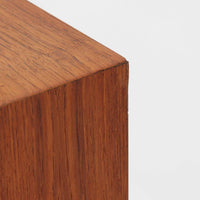 Kai Kristiansenがデザインし、Feldballes Mobelfabrikが製作した幅86cmの小ぶりなボードです。チーク材の美しい木目を活かした端正な箱型フォルムに、丸い引き手付きの引き戸がアクセントを添えます。内部には棚とトレー収納を備え、書類や小物を整理しやすい実用的な構造。すらりと伸びる脚部が軽やかさを演出し、限られた空間にも取り入れやすいサイズ感です。経年により深みを増した木肌が、北欧ビンテージならではの温もりと存在感を感じさせます。