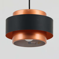 Jo HammerborgがFog & Morupのためにデザインした「Juno」は、直径24cmの扱いやすいサイズに、銅色のシェードとマットブラックのバンドを組み合わせた構築的なフォルムが印象的なスチール製ペンダントライトで、点灯時には上下から柔らかく光が漏れ、空間に落ち着いた陰影を生み出す北欧ビンテージ品です。ハーマボーらしいミニマルで彫刻的な造形が存在感を放ち、ダイニングやリビング、カウンター上のアクセント照明としても取り入れやすく、経年で深まった金属の質感がビンテージならではの魅力を一層引き立てています。