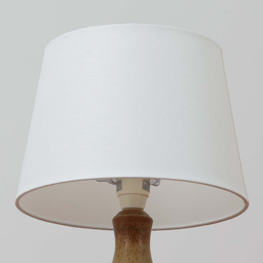 Soholm Keramik（スーホルム・セラミック）製のテーブルランプです。落ち着いたブラウンの陶磁器ボディに幾何学模様の装飾が施され、シンプルながらも存在感のあるデザインが魅力です。高さ38cmと扱いやすいサイズ感で、リビングや寝室のサイドテーブルに心地よい灯りを添えてくれます。北欧ビンテージならではの温かみある質感が、空間に柔らかな雰囲気をもたらします。