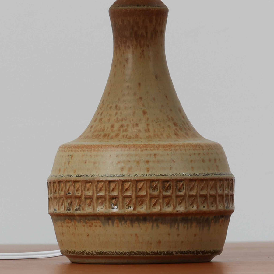 Soholm Keramik（スーホルム・セラミック）製のテーブルランプです。落ち着いたブラウンの陶磁器ボディに幾何学模様の装飾が施され、シンプルながらも存在感のあるデザインが魅力です。高さ38cmと扱いやすいサイズ感で、リビングや寝室のサイドテーブルに心地よい灯りを添えてくれます。北欧ビンテージならではの温かみある質感が、空間に柔らかな雰囲気をもたらします。