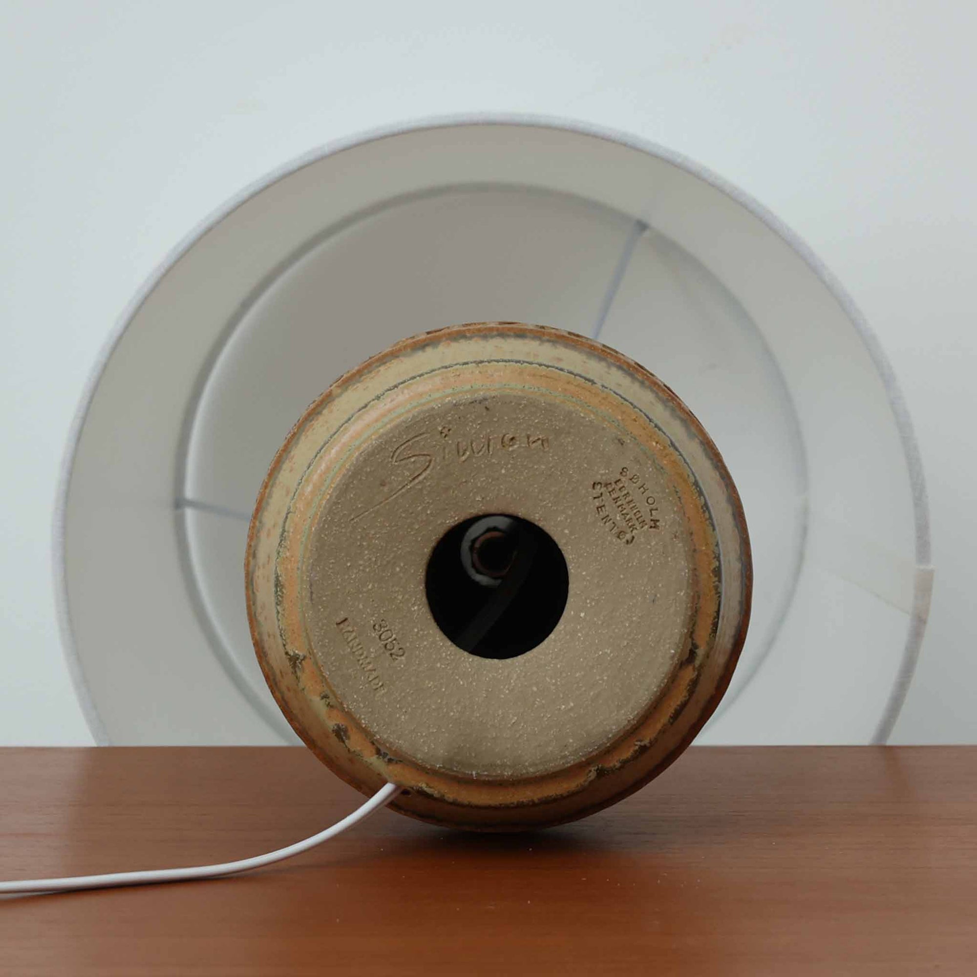 Soholm Keramik（スーホルム・セラミック）製のテーブルランプです。落ち着いたブラウンの陶磁器ボディに幾何学模様の装飾が施され、シンプルながらも存在感のあるデザインが魅力です。高さ38cmと扱いやすいサイズ感で、リビングや寝室のサイドテーブルに心地よい灯りを添えてくれます。北欧ビンテージならではの温かみある質感が、空間に柔らかな雰囲気をもたらします。