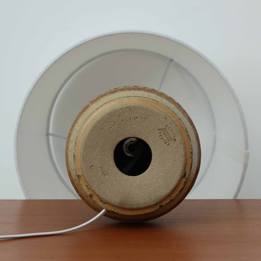 Soholm Keramik（スーホルム・セラミック）製のテーブルランプです。落ち着いたブラウンの陶磁器ボディに幾何学模様の装飾が施され、シンプルながらも存在感のあるデザインが魅力です。高さ38cmと扱いやすいサイズ感で、リビングや寝室のサイドテーブルに心地よい灯りを添えてくれます。北欧ビンテージならではの温かみある質感が、空間に柔らかな雰囲気をもたらします。