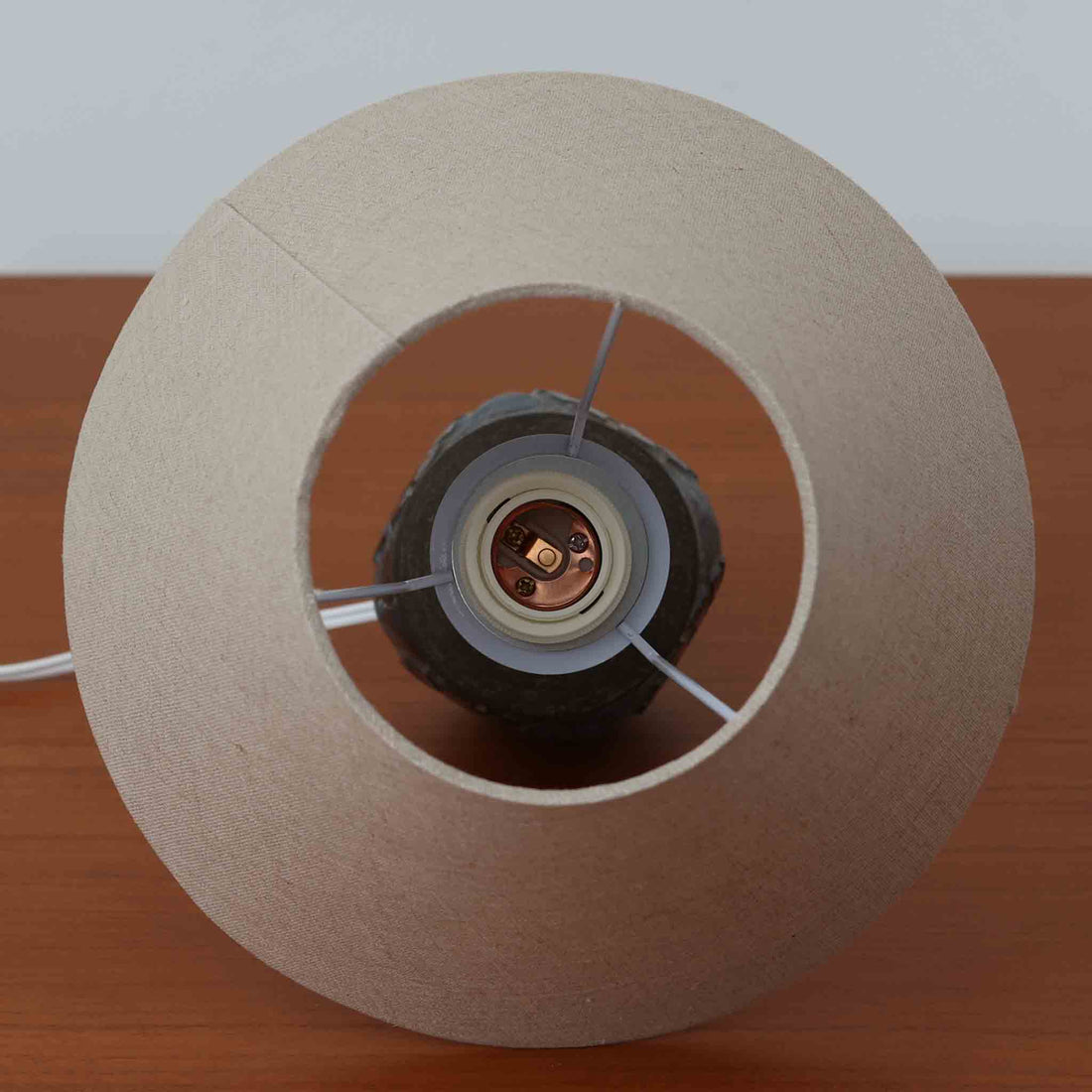 Chris HaslevがJetiのために手掛けたこちらのテーブルランプは、太陽を思わせるレリーフ模様をまとった陶器ベースと、素朴な土肌と釉薬の濃淡が織りなす豊かな表情が魅力で、コンパクトながら存在感を放つ北欧ビンテージ品です。上部のマットな質感が造形を引き締め、リネンシェード越しに広がるあたたかな灯りが空間をやさしく包み込み、リビングやベッドサイドのアクセントとして取り入れやすい一台に仕上がっています。