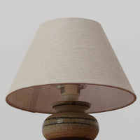 Axella製のこちらのテーブルランプは、素朴な陶土の質感と水平に重ねられた釉薬のグラデーションが生む落ち着いた佇まいが魅力で、ふくらみのある曲線的なベースと小ぶりなサイズ感が空間にさりげない温かみを添える北欧ビンテージ品です。リネンシェード越しに漏れる柔らかな灯りが陶肌の陰影をやさしく引き立て、デスクやベッドサイドなどにも取り入れやすく、経年で深まった素材の風合いが一点物ならではの味わいを感じさせてくれます。