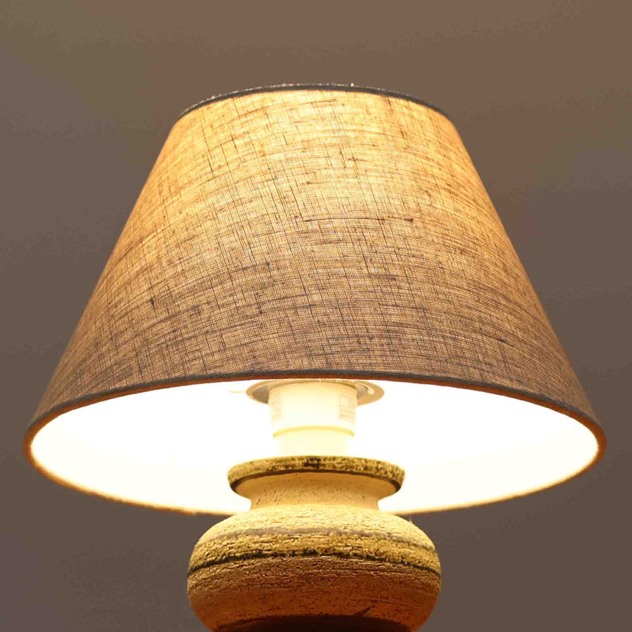 Axella製のこちらのテーブルランプは、素朴な陶土の質感と水平に重ねられた釉薬のグラデーションが生む落ち着いた佇まいが魅力で、ふくらみのある曲線的なベースと小ぶりなサイズ感が空間にさりげない温かみを添える北欧ビンテージ品です。リネンシェード越しに漏れる柔らかな灯りが陶肌の陰影をやさしく引き立て、デスクやベッドサイドなどにも取り入れやすく、経年で深まった素材の風合いが一点物ならではの味わいを感じさせてくれます。