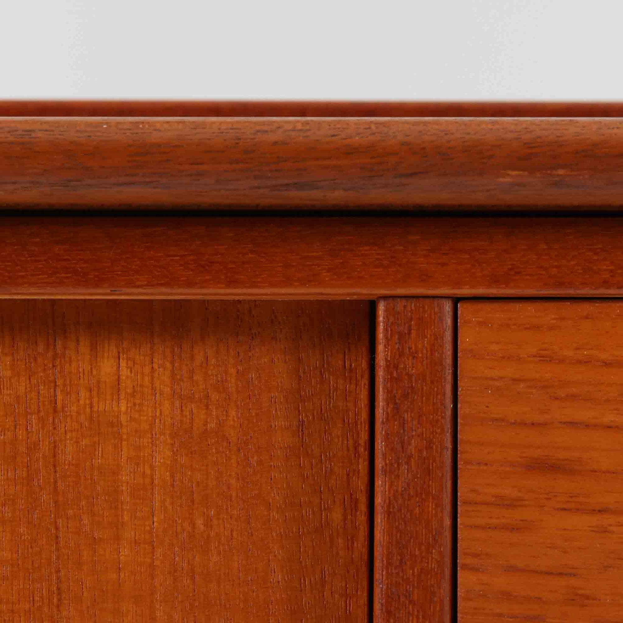 チーク材とビーチ材を組み合わせた北欧ビンテージらしい佇まいが魅力のディスプレイシェルフで、直線的で端正なフレーム構成と、木目の表情を活かした温かみのある質感が空間に落ち着きをもたらします。上部のオープン棚は器や書籍、オブジェの展示に適しており、下部には引き戸収納と引き出しを備えることで、見せる収納と隠す収納をバランス良く両立しています。脚付き構造により圧迫感が少なく、リビングやダイニング、書斎など幅広いシーンで活躍し、経年変化による色味の深まりも楽しめる一台です。