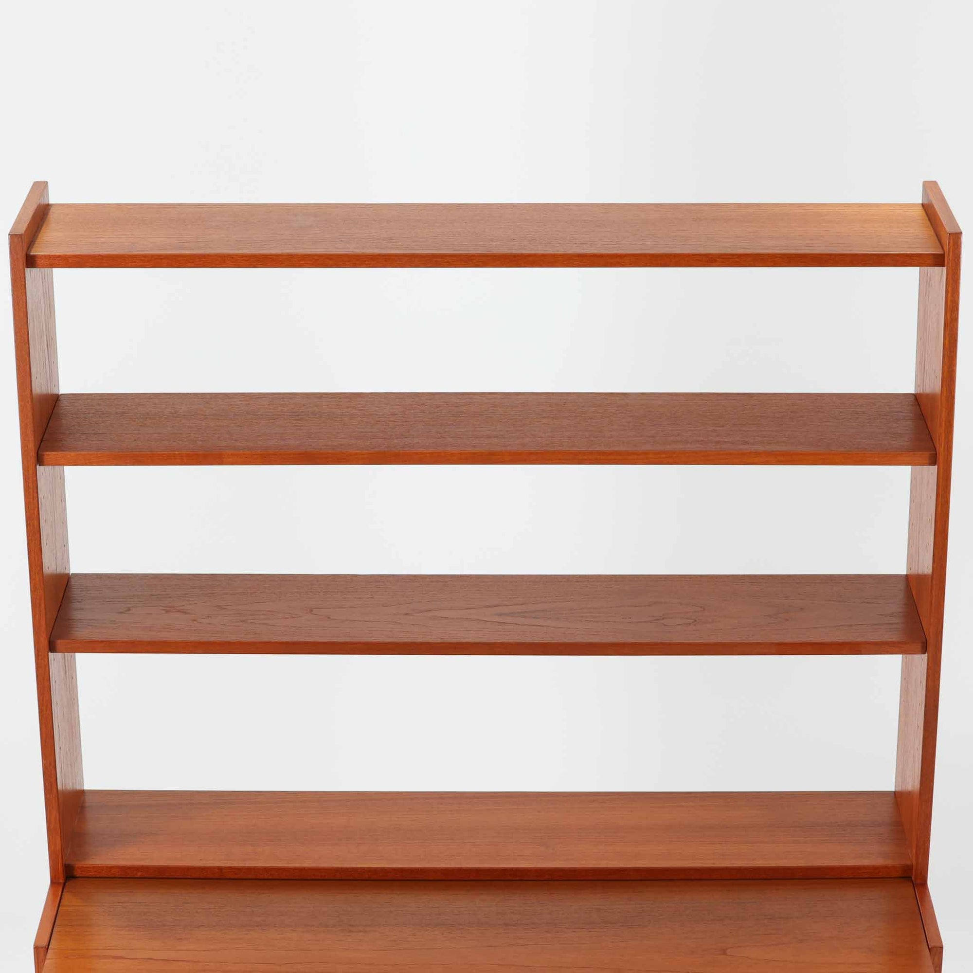 チーク材とビーチ材を組み合わせた北欧ビンテージらしい佇まいが魅力のディスプレイシェルフで、直線的で端正なフレーム構成と、木目の表情を活かした温かみのある質感が空間に落ち着きをもたらします。上部のオープン棚は器や書籍、オブジェの展示に適しており、下部には引き戸収納と引き出しを備えることで、見せる収納と隠す収納をバランス良く両立しています。脚付き構造により圧迫感が少なく、リビングやダイニング、書斎など幅広いシーンで活躍し、経年変化による色味の深まりも楽しめる一台です。