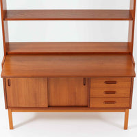 チーク材とビーチ材を組み合わせた北欧ビンテージらしい佇まいが魅力のディスプレイシェルフで、直線的で端正なフレーム構成と、木目の表情を活かした温かみのある質感が空間に落ち着きをもたらします。上部のオープン棚は器や書籍、オブジェの展示に適しており、下部には引き戸収納と引き出しを備えることで、見せる収納と隠す収納をバランス良く両立しています。脚付き構造により圧迫感が少なく、リビングやダイニング、書斎など幅広いシーンで活躍し、経年変化による色味の深まりも楽しめる一台です。