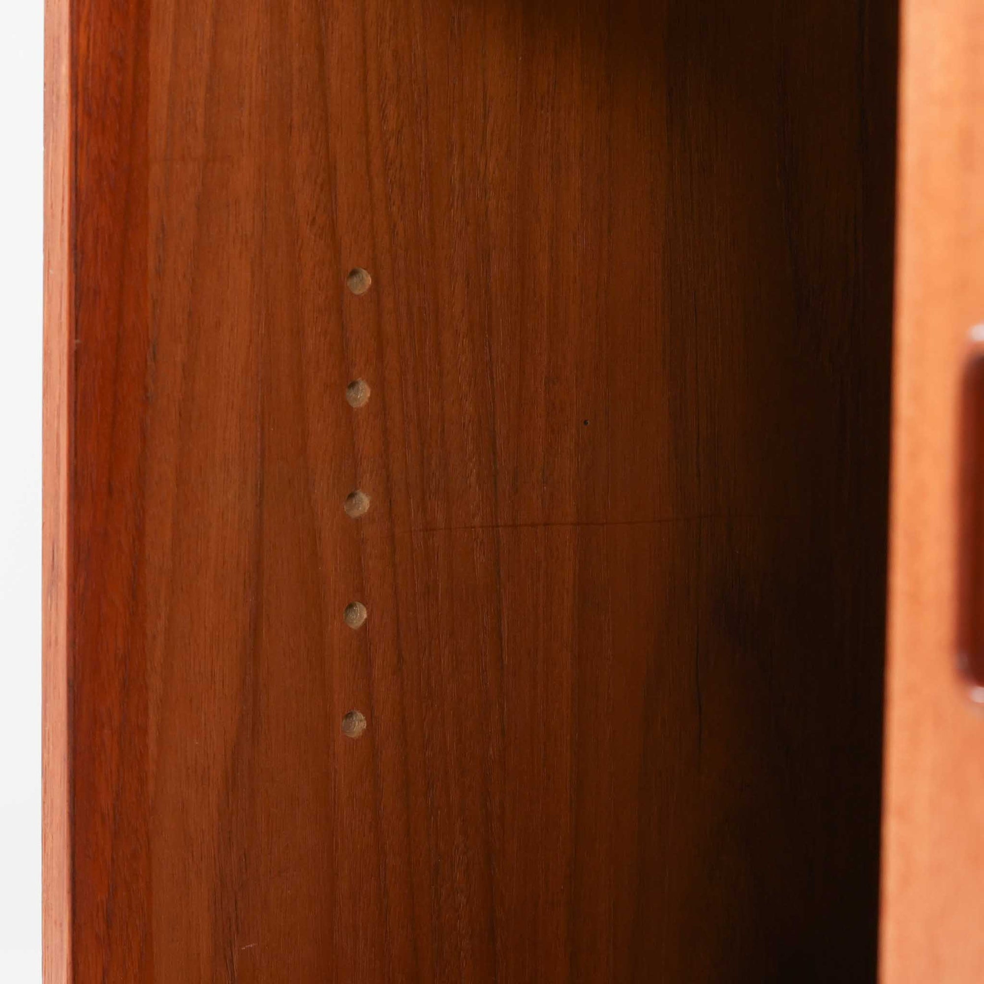 チーク材とビーチ材を組み合わせた北欧ビンテージらしい佇まいが魅力のディスプレイシェルフで、直線的で端正なフレーム構成と、木目の表情を活かした温かみのある質感が空間に落ち着きをもたらします。上部のオープン棚は器や書籍、オブジェの展示に適しており、下部には引き戸収納と引き出しを備えることで、見せる収納と隠す収納をバランス良く両立しています。脚付き構造により圧迫感が少なく、リビングやダイニング、書斎など幅広いシーンで活躍し、経年変化による色味の深まりも楽しめる一台です。