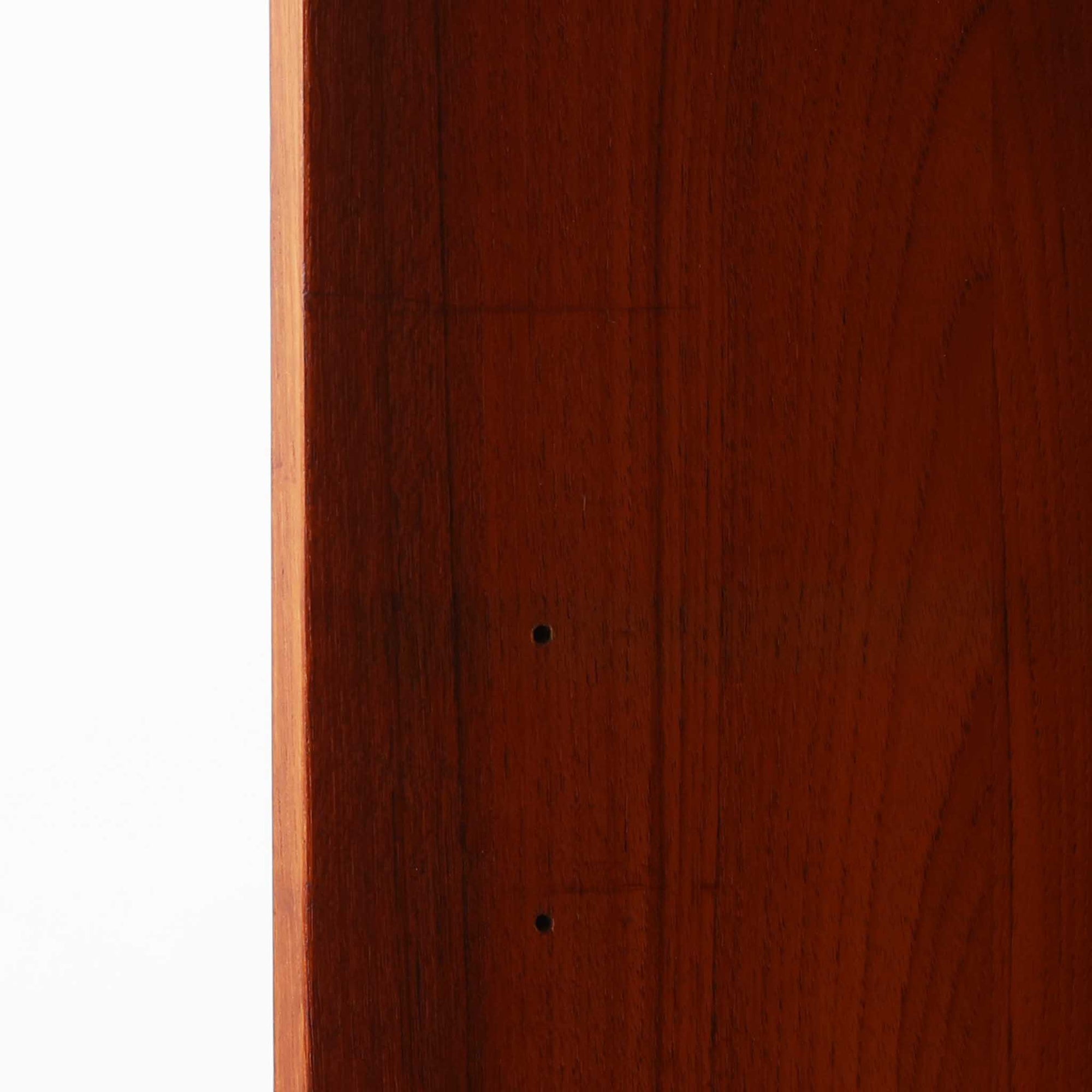 Asljunga Mobelfabrikによるディスプレイシェルフは、チーク材とビーチ材を組み合わせた端正な佇まいが魅力の北欧ビンテージ家具です。上段はオープンシェルフ構造で、棚板を活かした見せる収納が楽しめ、下段には引き戸式の収納部を備えることで実用性も確保されています。直線的で無駄のないフォルムに、掘り込み式の取っ手や脚部の軽やかなバランスが北欧らしい品の良さを添え、幅79cmの程よいサイズ感はリビングやダイニング、書斎など幅広い空間に取り入れやすく、経年変化によって深みを増した木肌と丁寧な造りが静かな存在感を放つ一台です。