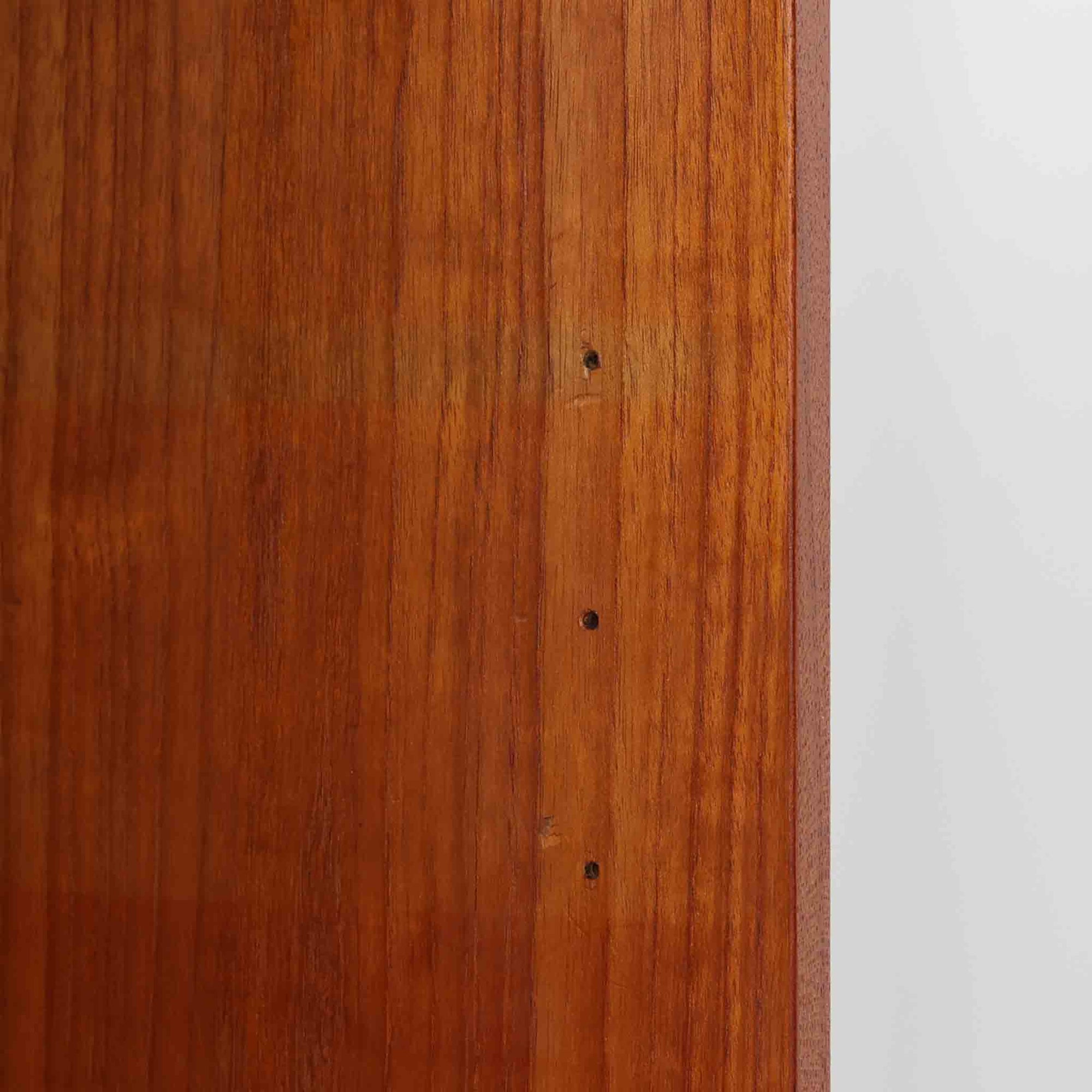 Asljunga Mobelfabrikによるディスプレイシェルフは、チーク材とビーチ材を組み合わせた端正な佇まいが魅力の北欧ビンテージ家具です。上段はオープンシェルフ構造で、棚板を活かした見せる収納が楽しめ、下段には引き戸式の収納部を備えることで実用性も確保されています。直線的で無駄のないフォルムに、掘り込み式の取っ手や脚部の軽やかなバランスが北欧らしい品の良さを添え、幅79cmの程よいサイズ感はリビングやダイニング、書斎など幅広い空間に取り入れやすく、経年変化によって深みを増した木肌と丁寧な造りが静かな存在感を放つ一台です。